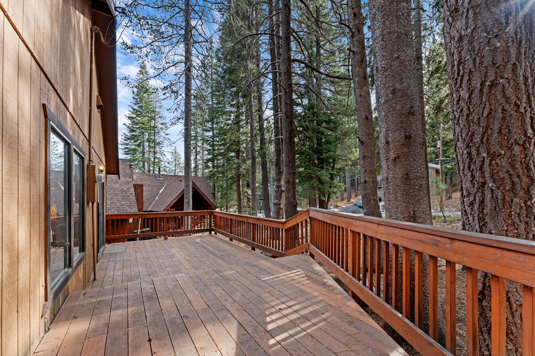 Spacious wooden deck at a Truckee vacation rental, surrounded by tall pine trees and rustic cabin-style architecture.