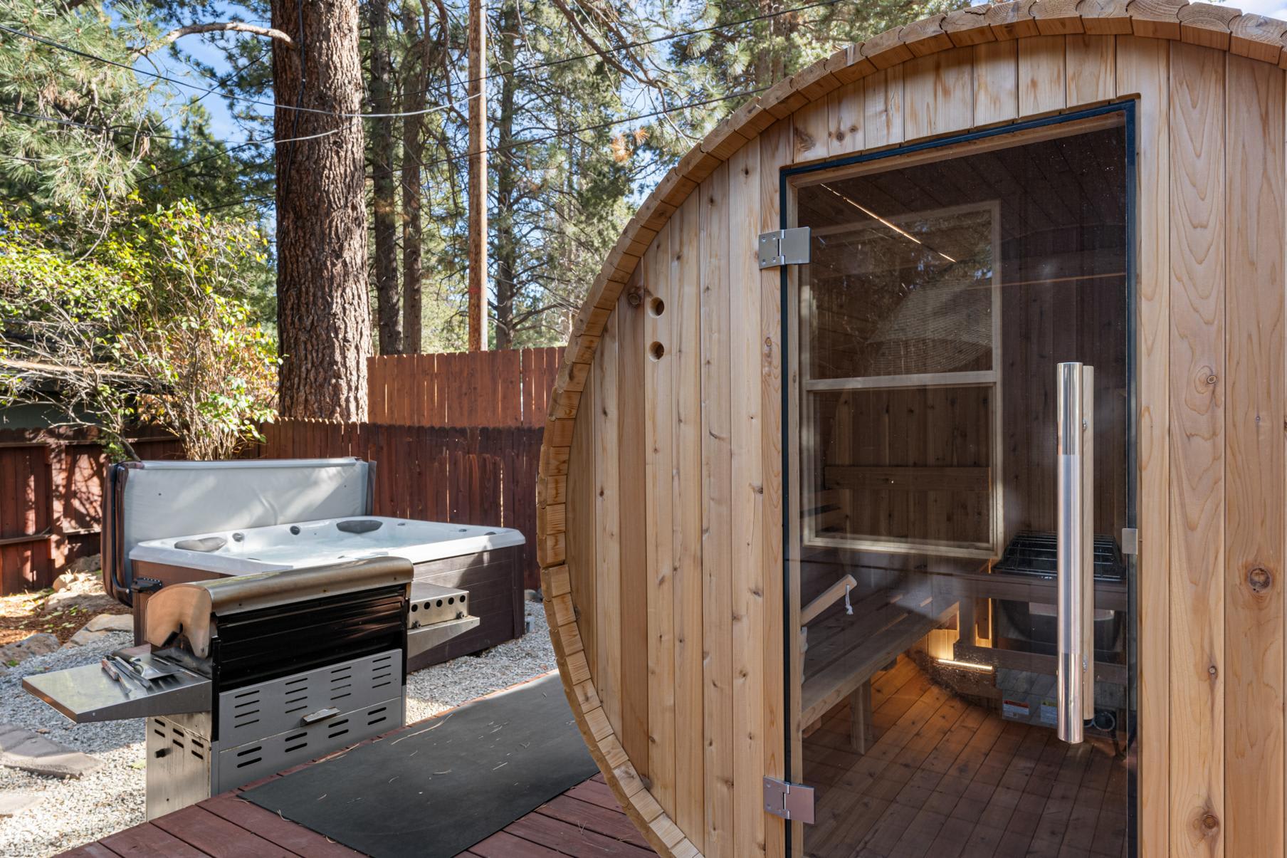 Sauna and hot tub at a Truckee vacation rental, set in a fenced yard with tall trees in the background.