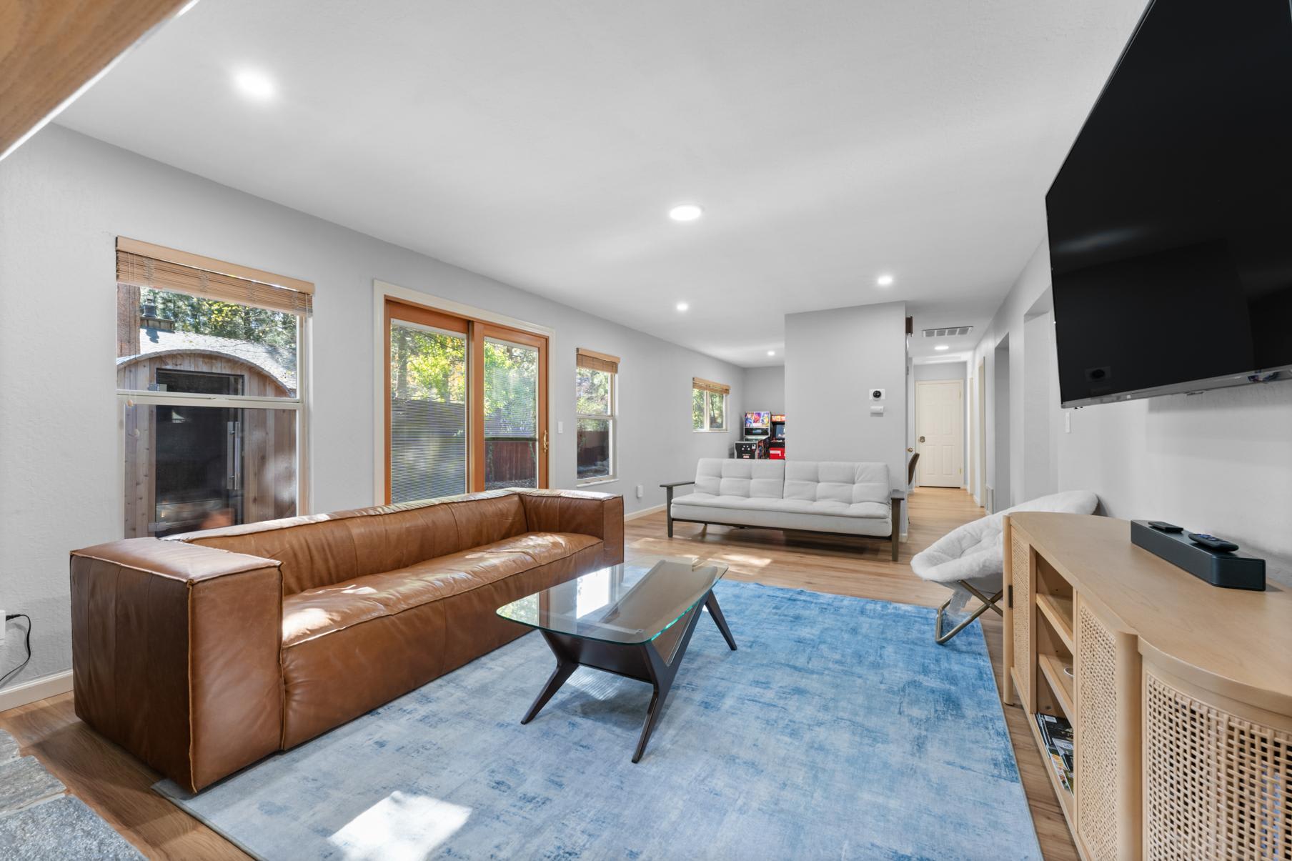 Modern living room in a Truckee vacation rental with leather sofa, TV, and arcade game.