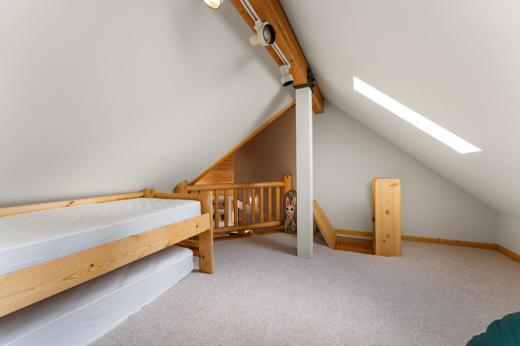 Loft area with wooden bed frames in a Truckee vacation rental, featuring sloped ceiling and natural light.