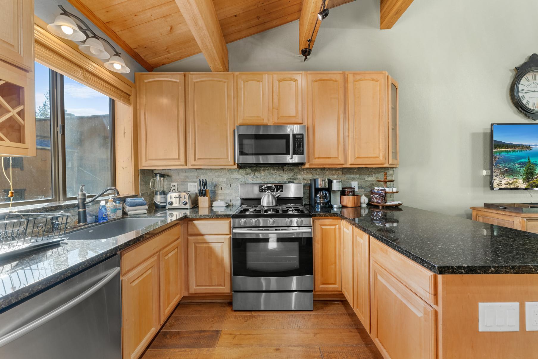 Modern kitchen in a Truckee vacation rental featuring wooden cabinets, granite countertops, and stainless steel appliances.