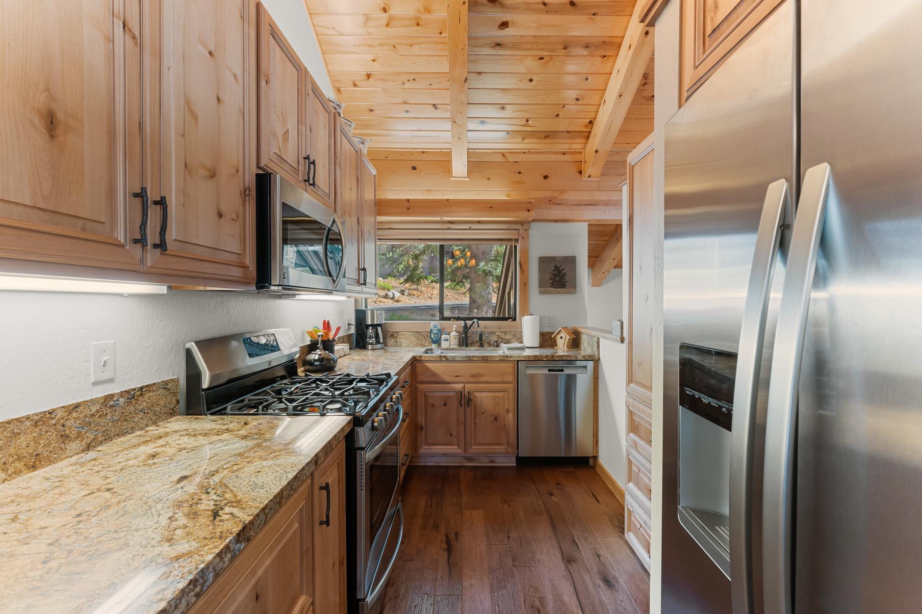 Modern kitchen with wooden cabinets and stainless steel appliances in a Truckee vacation rental, featuring rustic charm.