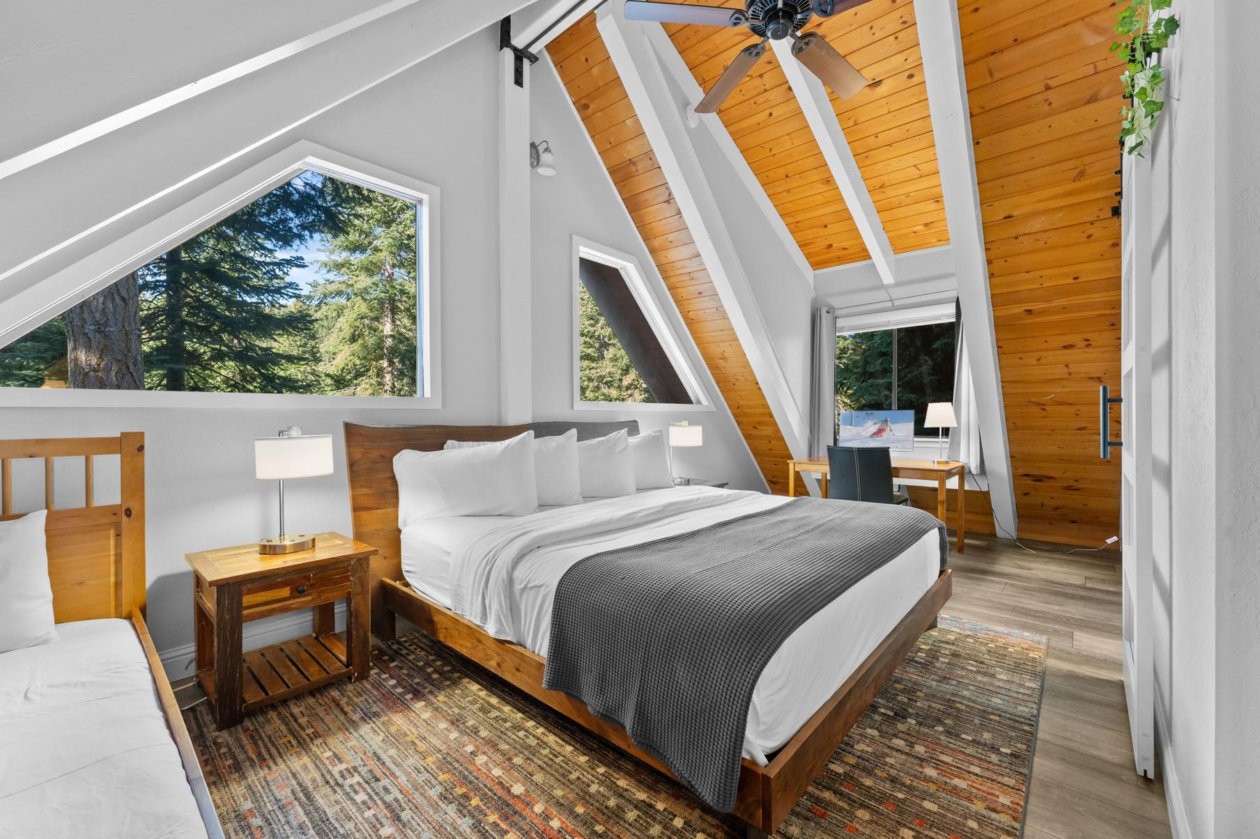 Cozy A-frame bedroom with wooden accents in a Tahoe Vista vacation rental, featuring large windows and forest views.