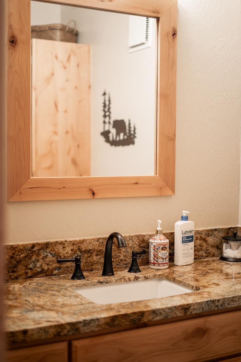 Bathroom with granite countertop in a Truckee vacation rental, featuring a wooden mirror and toiletries.