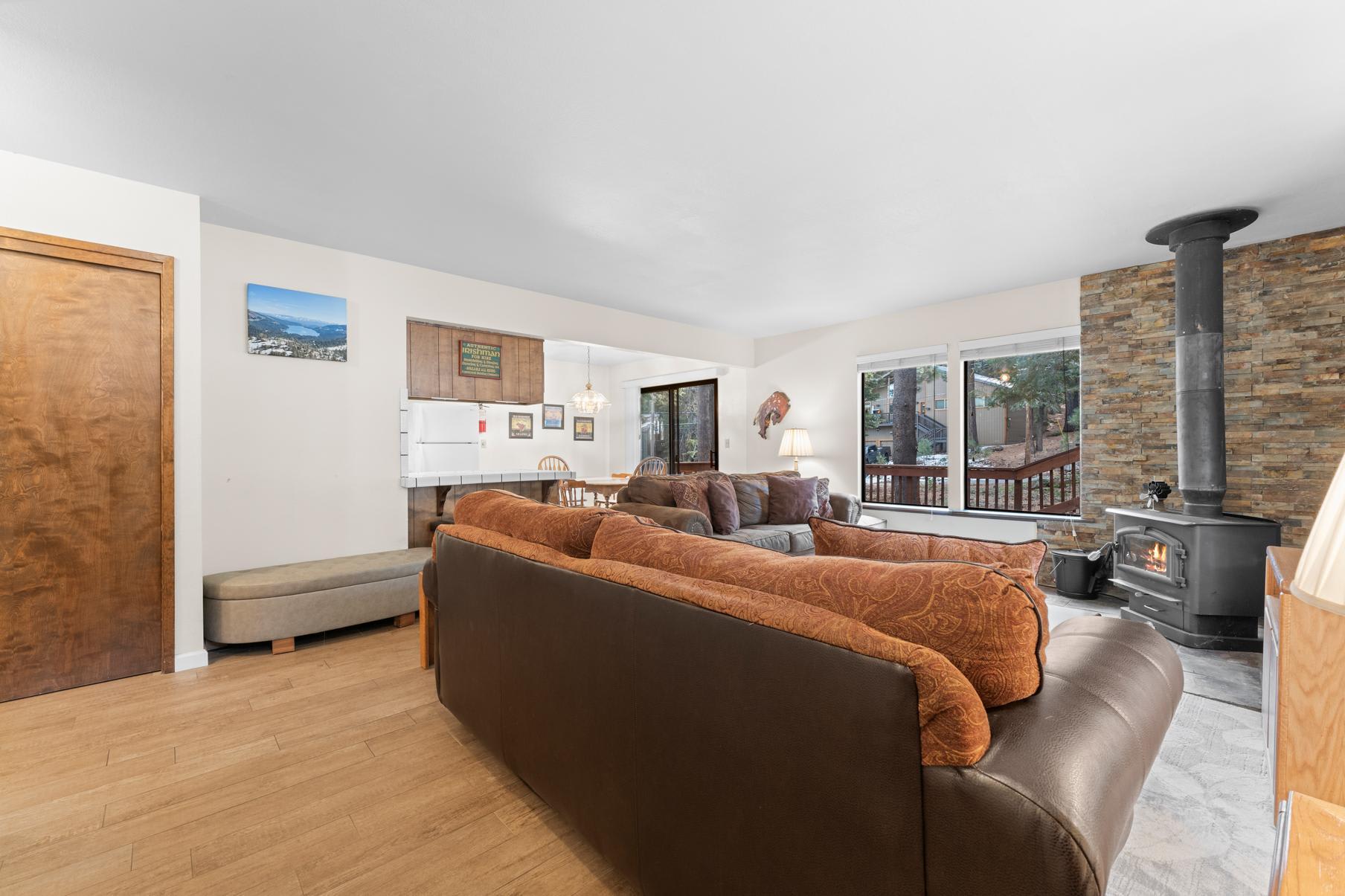 Cozy living room with a wood stove in a Truckee vacation rental, featuring large windows and comfortable seating.