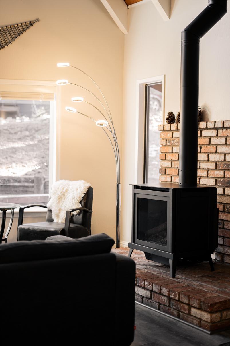 Cozy Tahoe Vista vacation rental living room with modern fireplace, stylish chair, and floor lamp by a window.