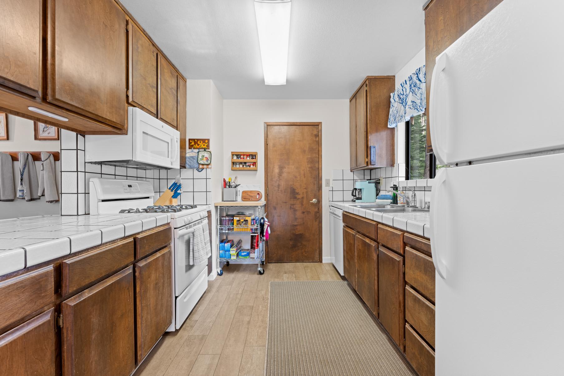 Kitchen in a Truckee vacation rental, featuring wooden cabinets, white appliances, and natural light from a window.