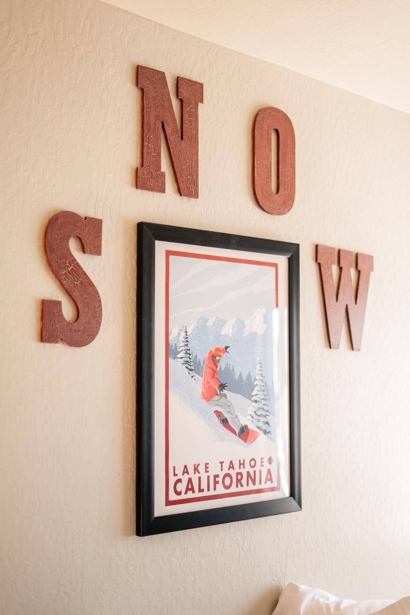 Wall art in Truckee vacation rental featuring Lake Tahoe snowboarding poster and wooden "SNOW" letters.