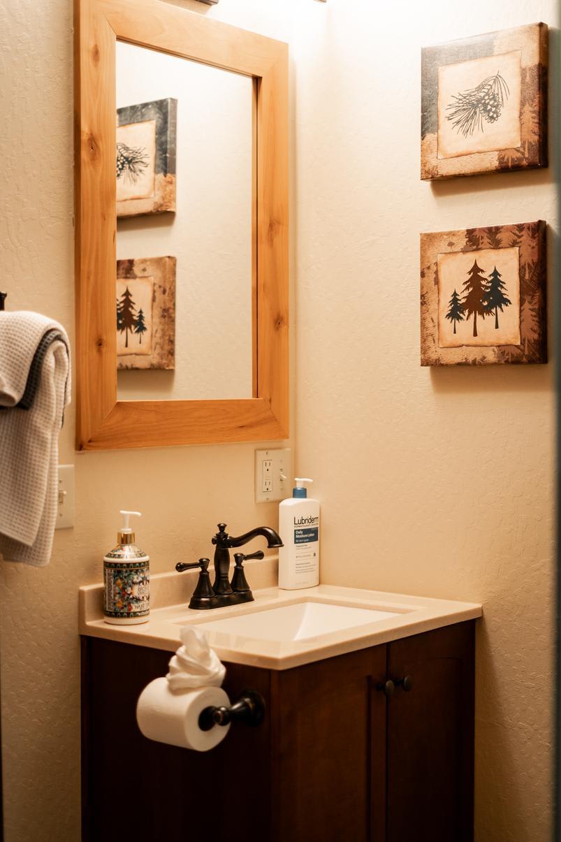 Cozy bathroom in a Truckee vacation rental, featuring a wooden framed mirror and nature-themed wall art.