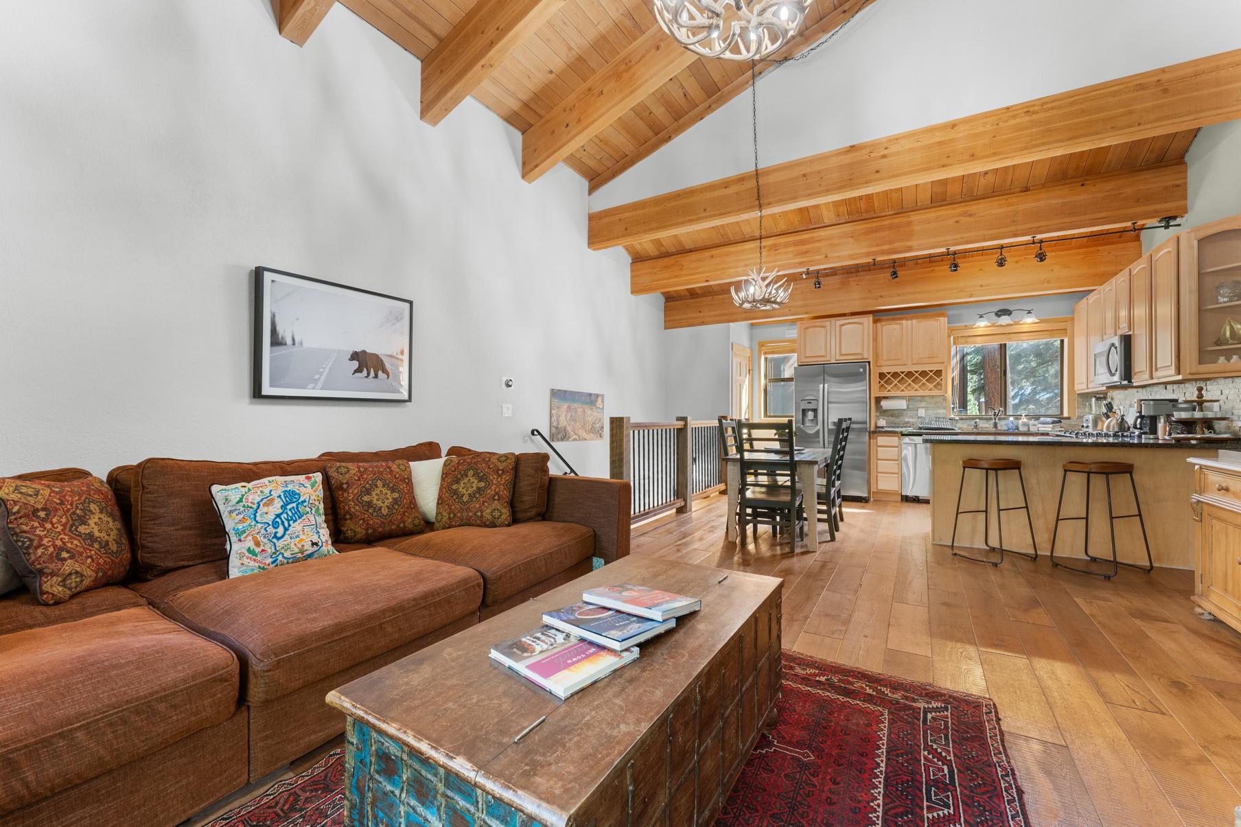 Cozy Truckee vacation rental with wooden beams, rustic decor, and a modern kitchen, featuring a comfy sofa and dining area.