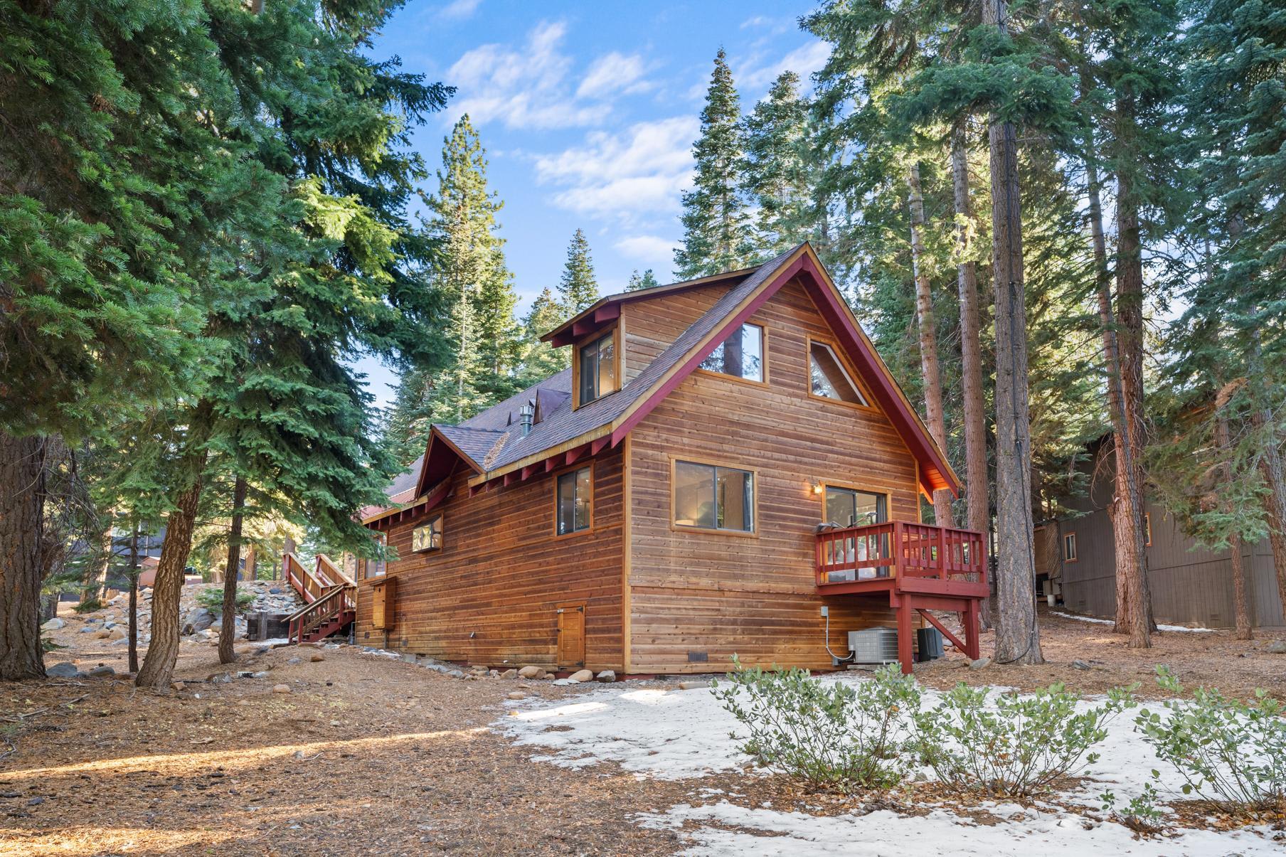 Rustic wooden cabin vacation rental nestled among tall trees in Tahoe Vista, with a snowy patch in the foreground.