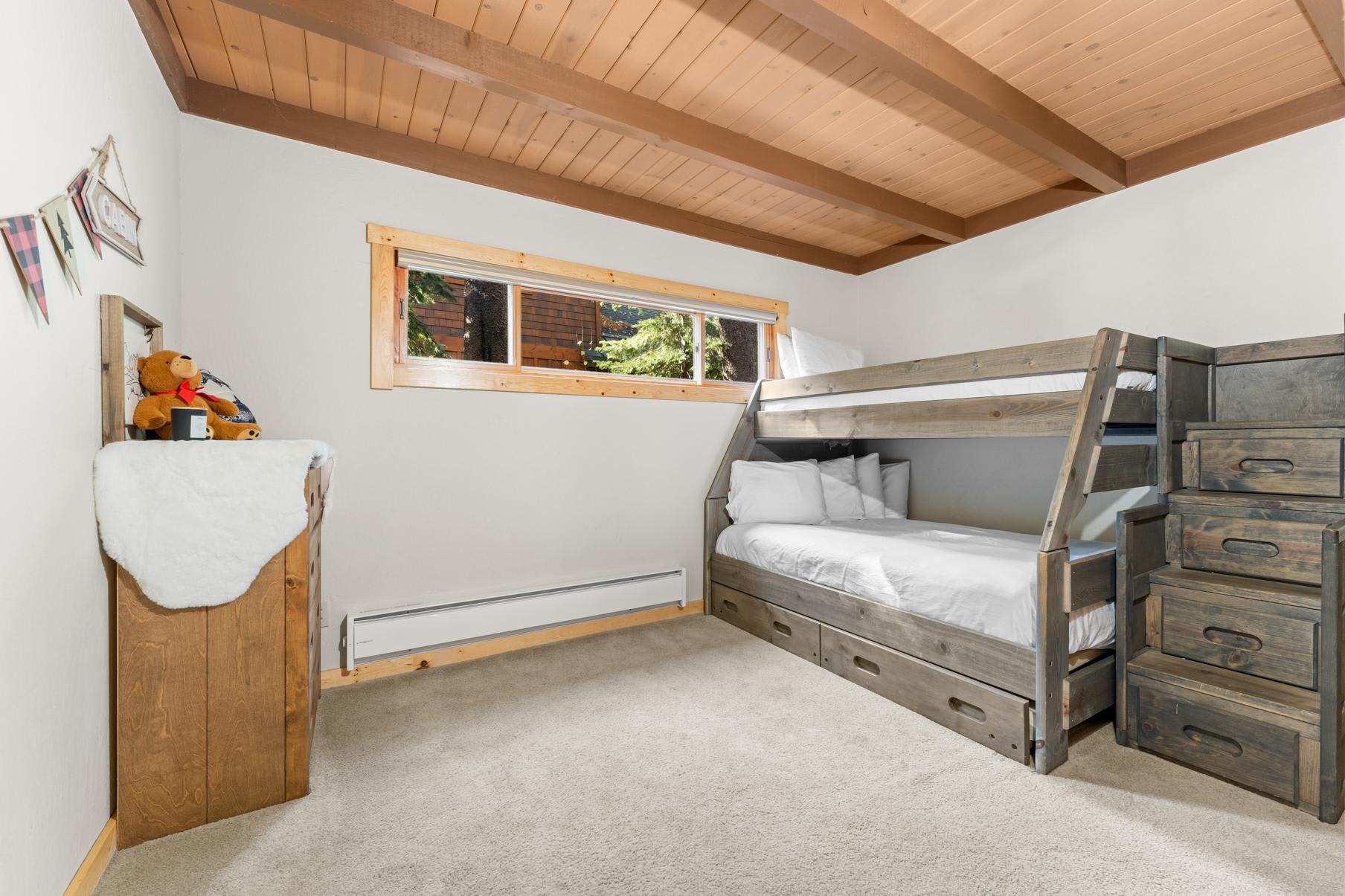 Bunk bed room in a cozy Truckee vacation rental with wooden ceiling and forest view.