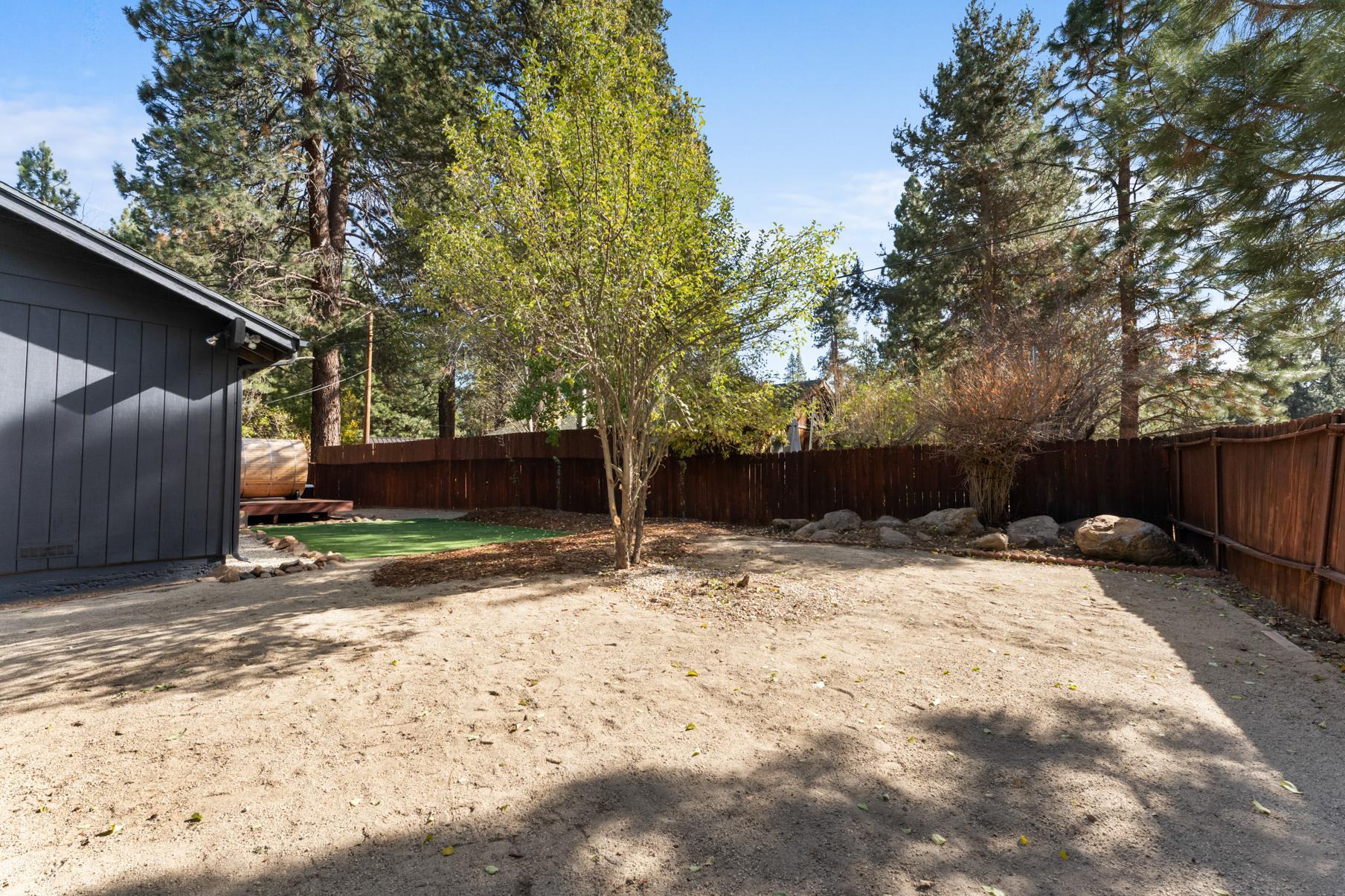 Backyard of a Truckee vacation rental with trees, a fenced yard, and a wooden deck.