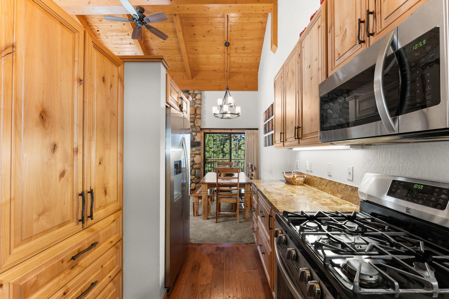 Wooden kitchen in Truckee vacation rental, with stainless appliances, stone fireplace, and dining table by a window.