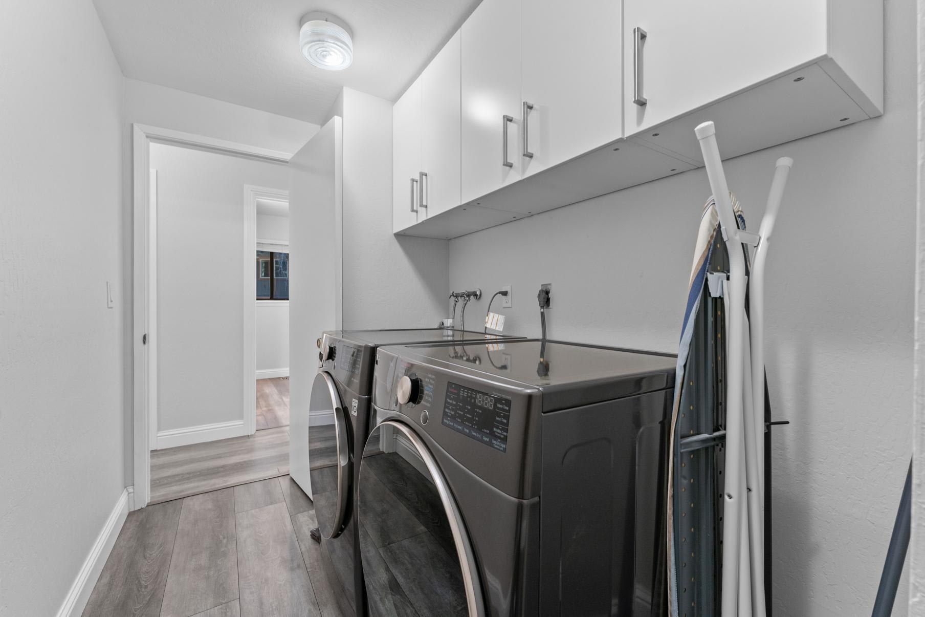 Laundry room in a Tahoe Vista vacation rental with modern washer, dryer, and white cabinets.