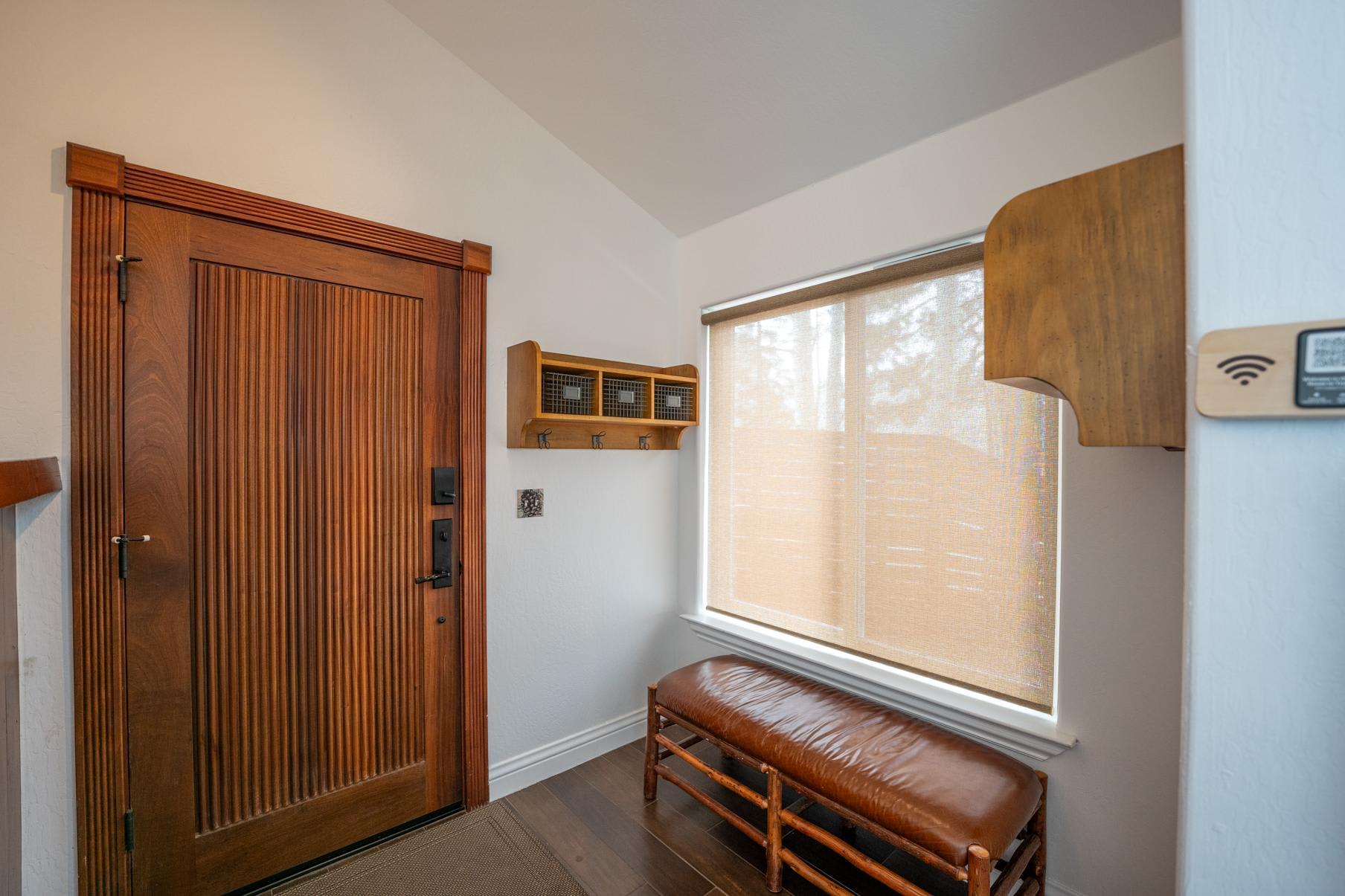 Entrance in Truckee vacation rental with wooden door, bench, coat rack, and window with blind.