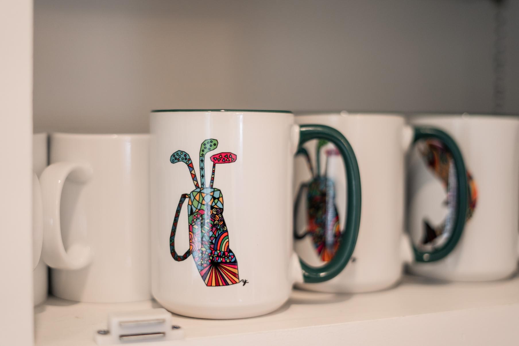 Colorful golf-themed mugs in a Truckee vacation rental kitchen cabinet.