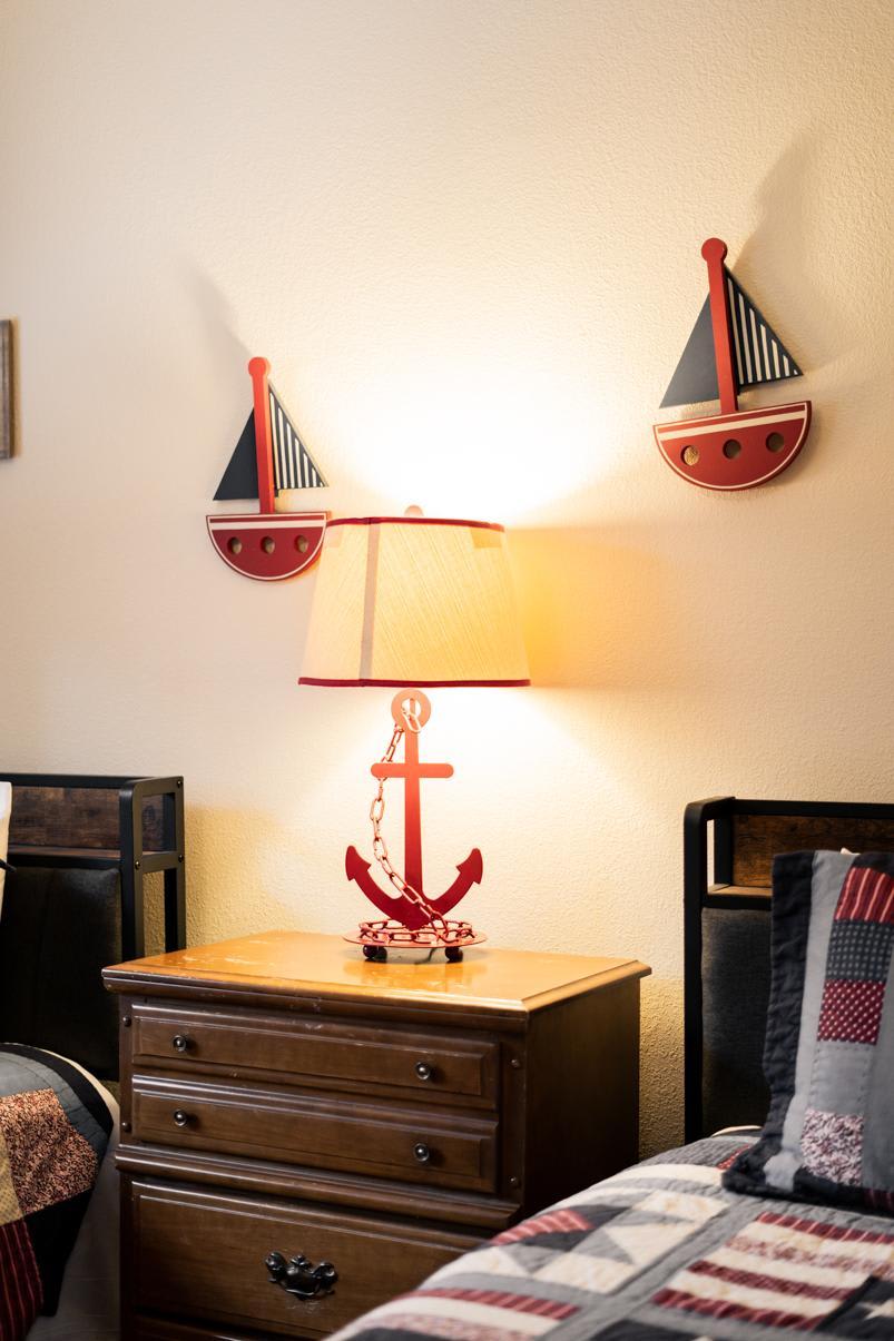 Cozy Truckee vacation rental bedroom with nautical decor, featuring an anchor lamp and sailboat wall art.