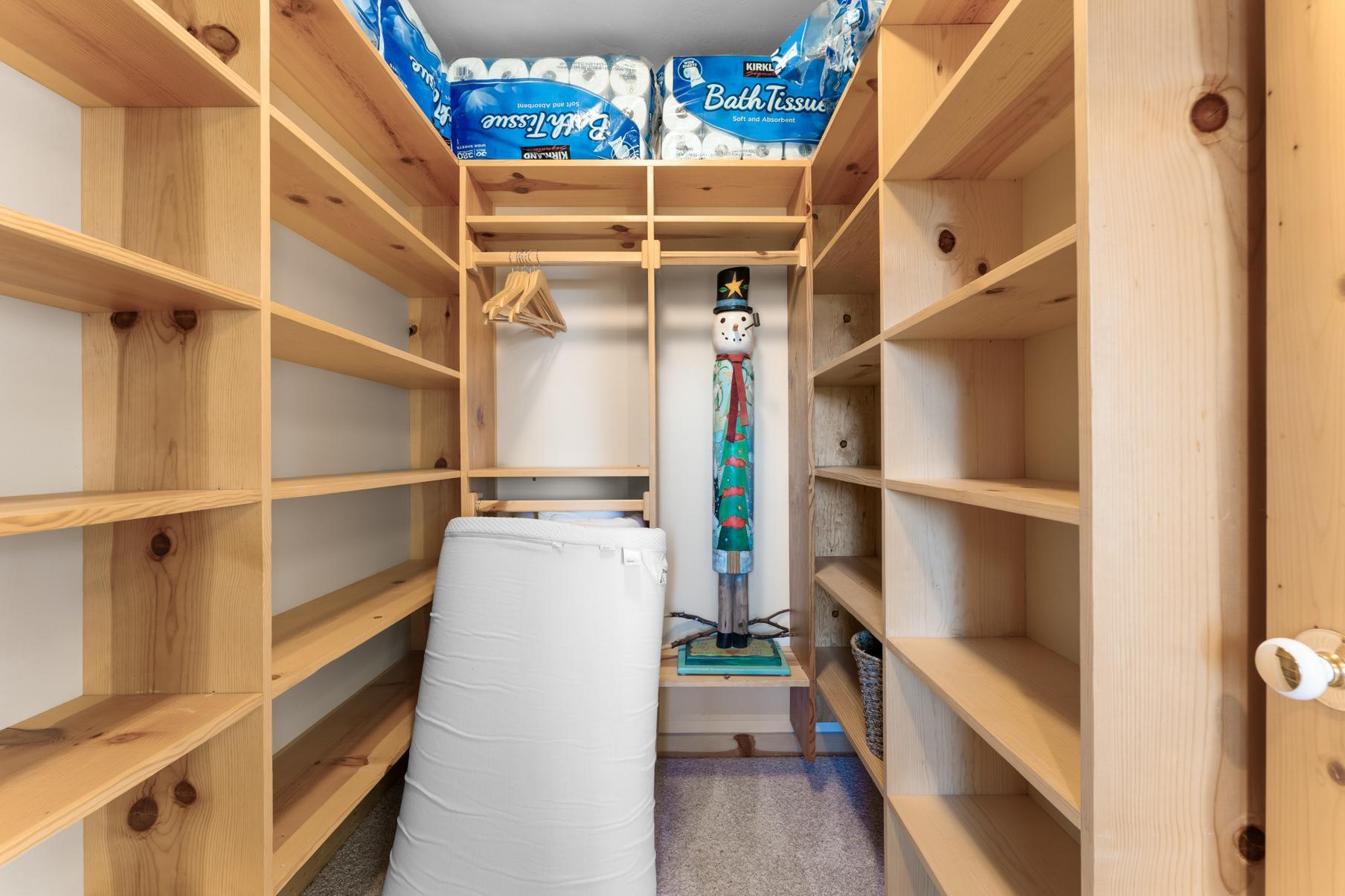 Wooden storage shelves in a Truckee vacation rental, stocked with bath tissue and featuring a whimsical snowman decoration.