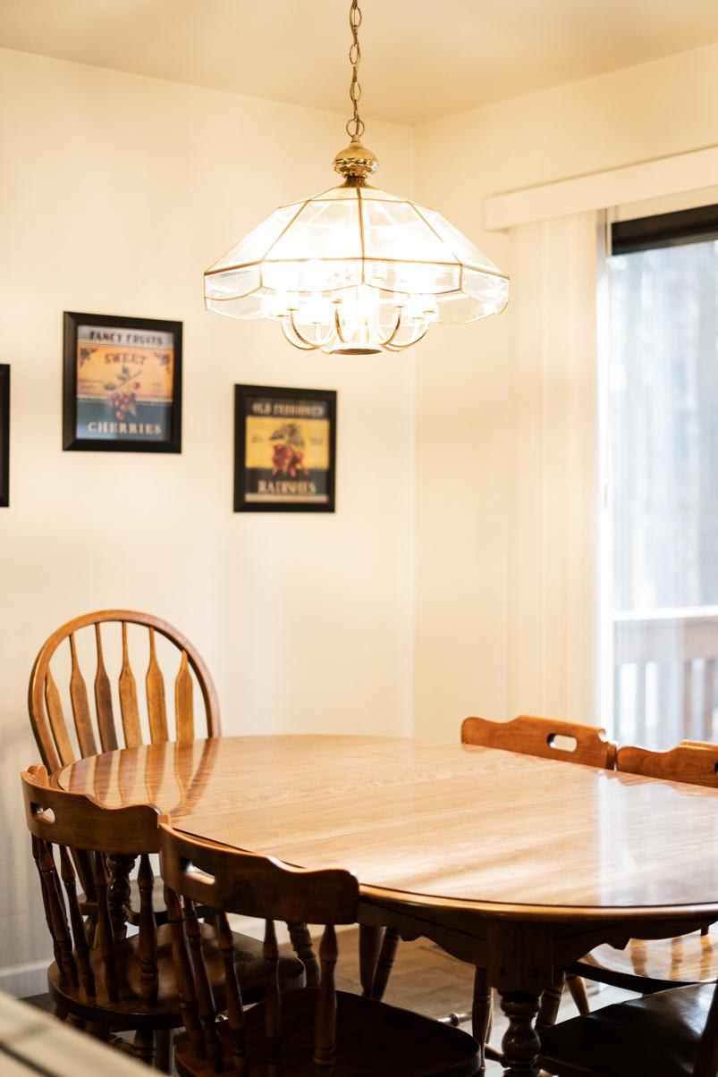 Cozy dining area in a Truckee vacation rental with a wooden table, chairs, and a decorative chandelier overhead.