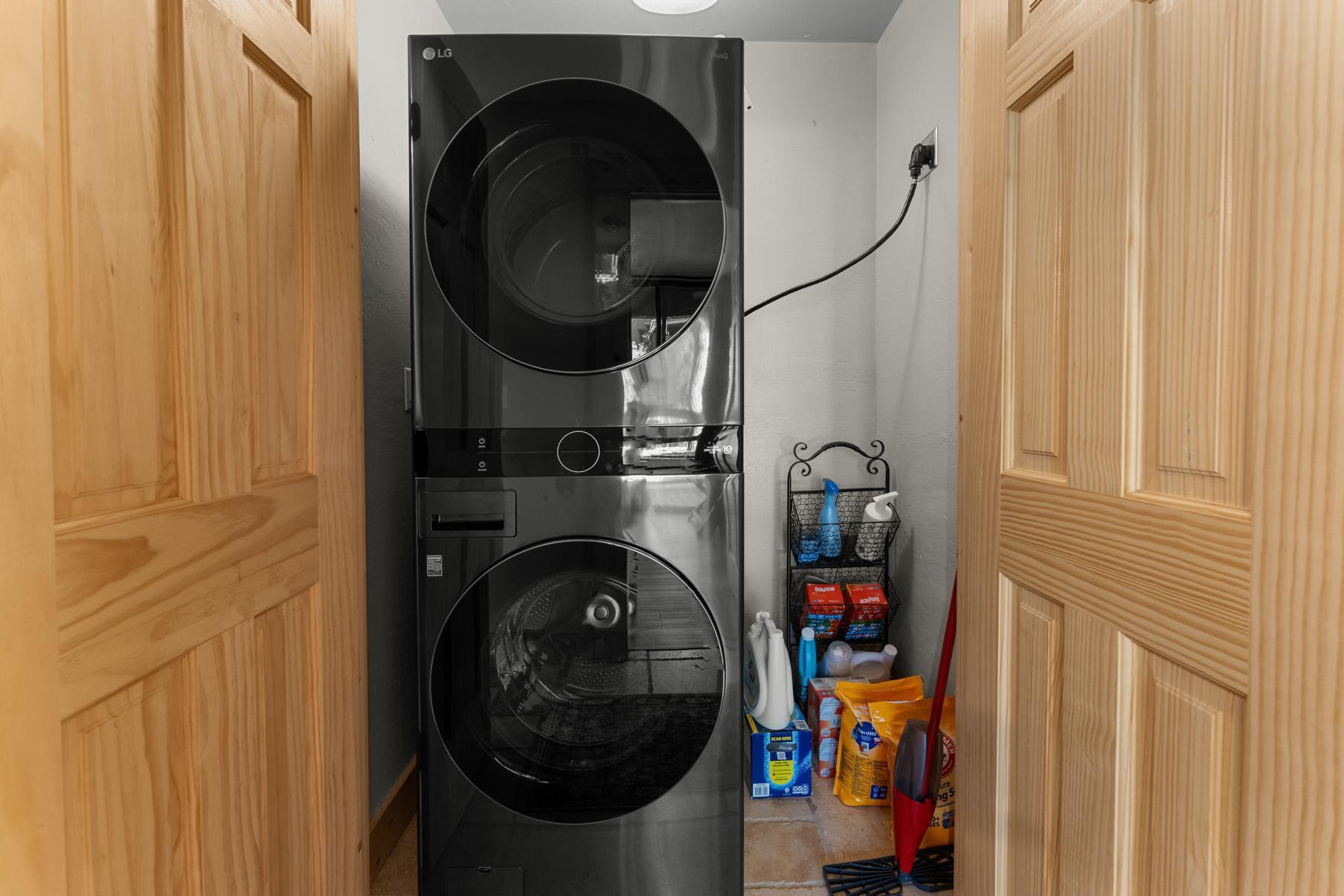 Stacked washer and dryer in a Truckee vacation rental, with cleaning supplies stored nearby.