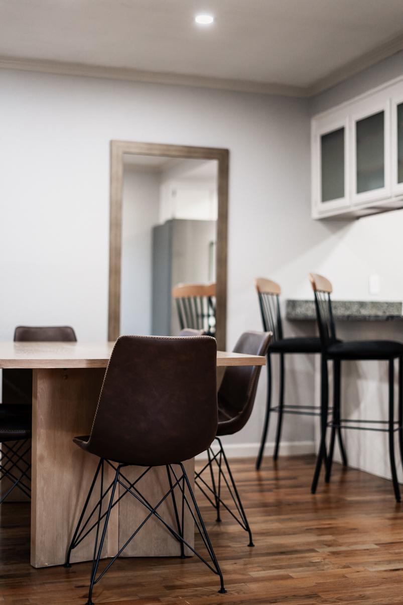 Modern dining area in a Truckee vacation rental, featuring wooden floors, leather chairs, and a wall mirror.