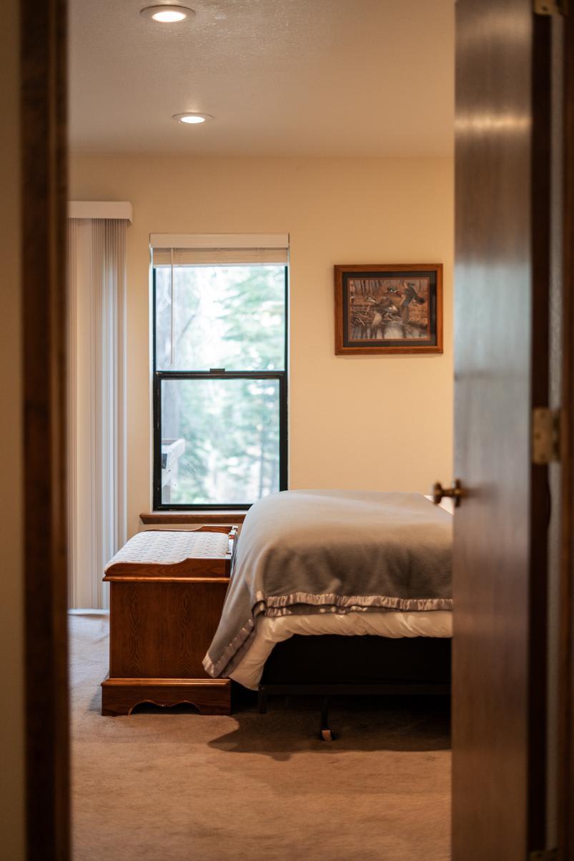 Cozy bedroom in a Truckee vacation rental, featuring a bed with a window view and framed animal artwork on the wall.