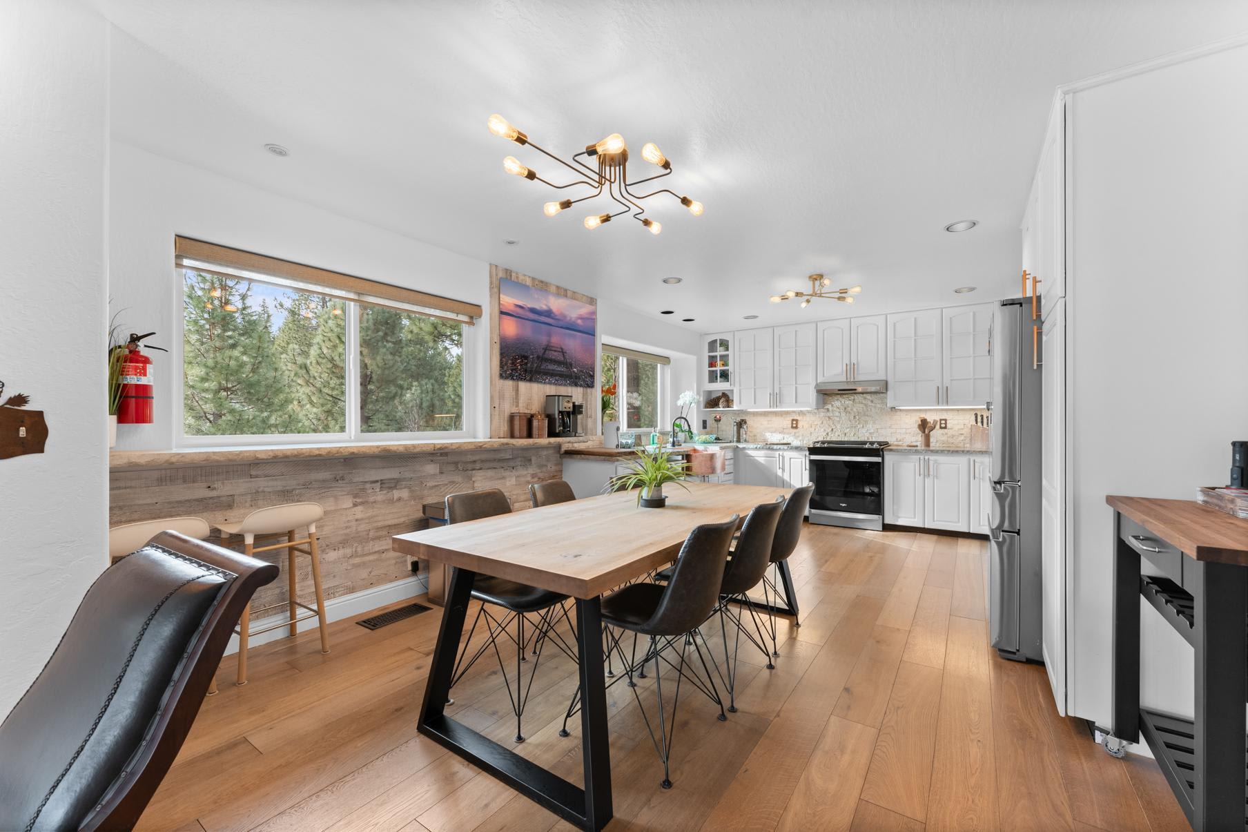 Modern kitchen and dining area in a Truckee vacation rental, featuring a large wooden table and elegant lighting.