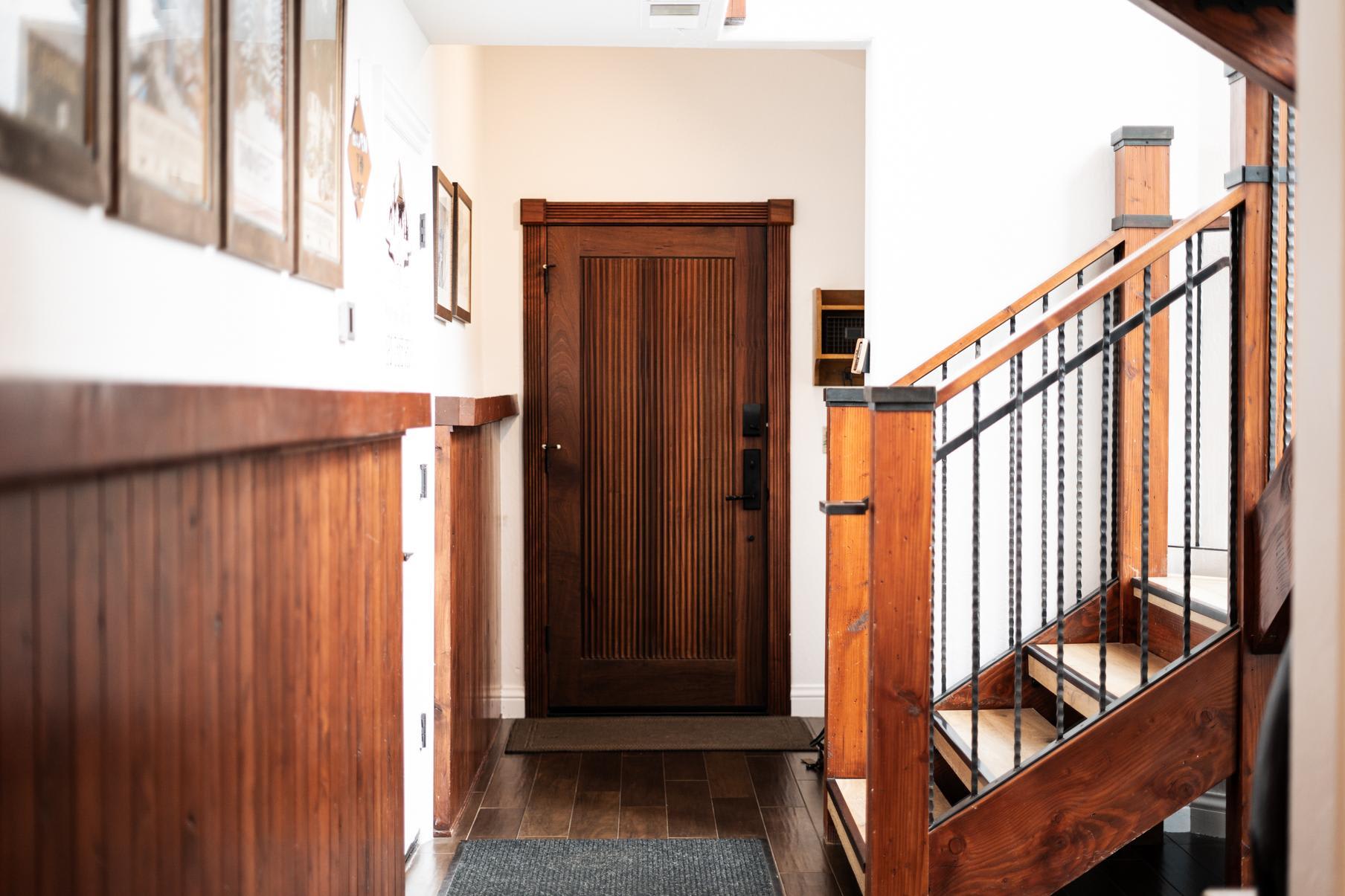 Entrance hallway with wooden door and stairs in a Truckee vacation rental, featuring rustic decor and natural light.