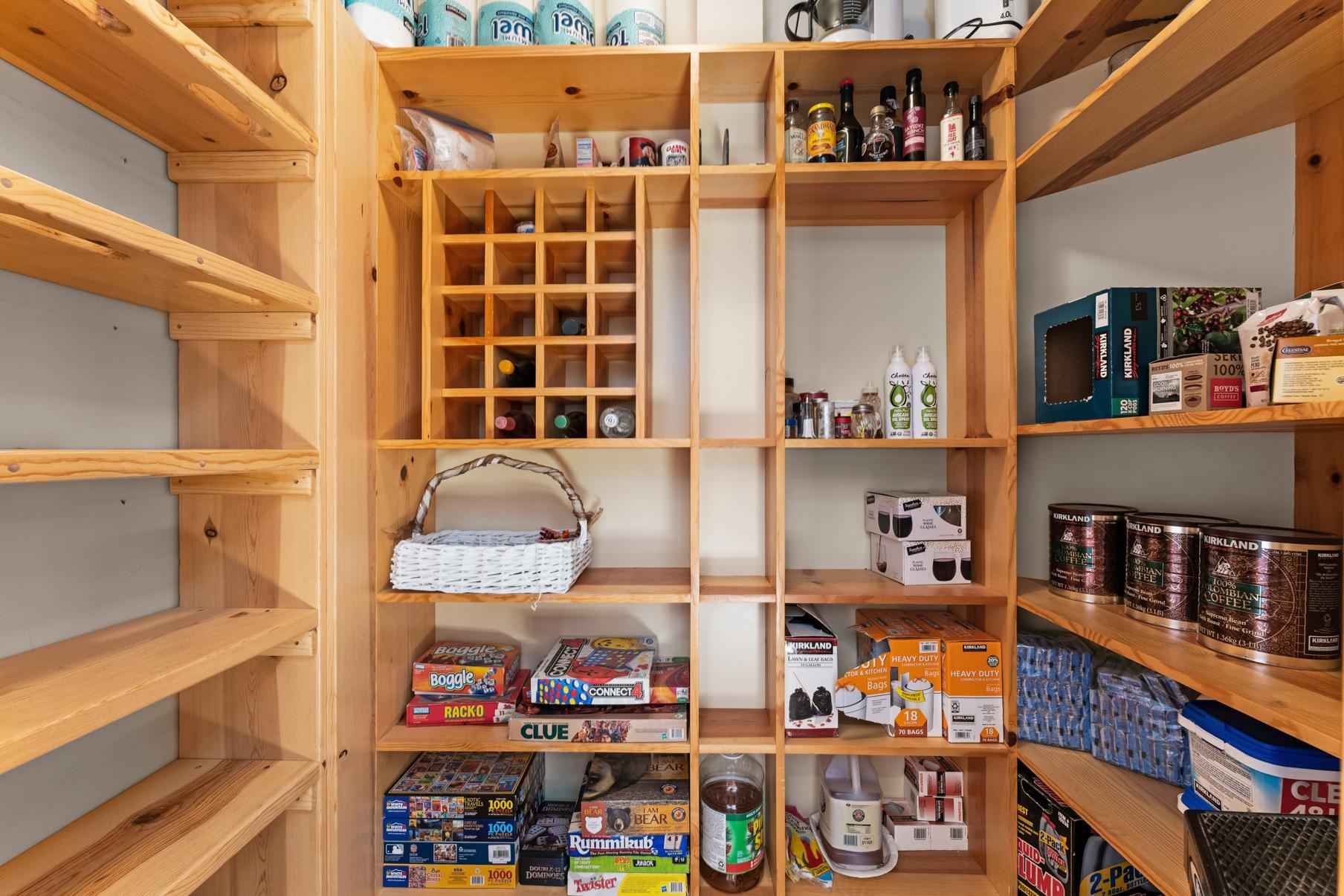 Pantry in Truckee vacation rental with board games, wine rack, and shelves stocked with various household items.