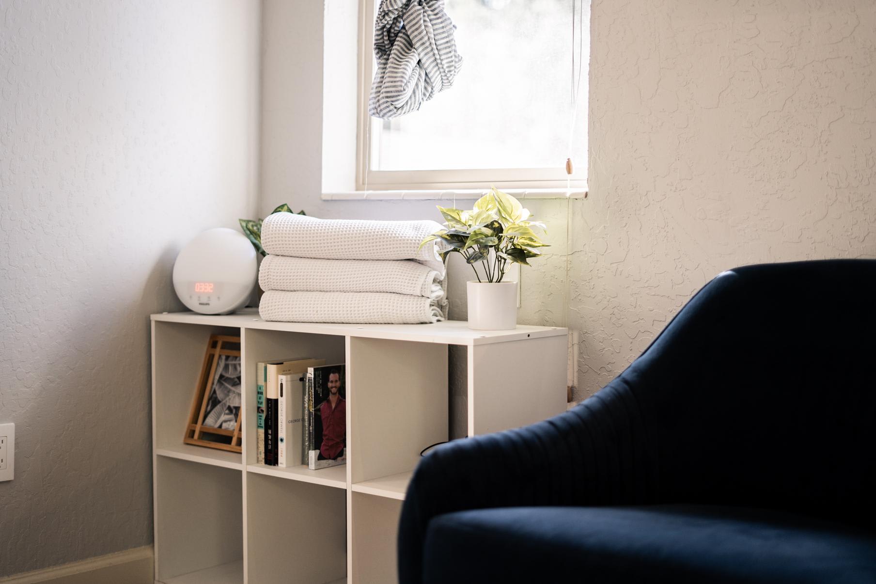 Cozy corner in a Truckee vacation rental with books, clock, and plant on a shelf near a window.