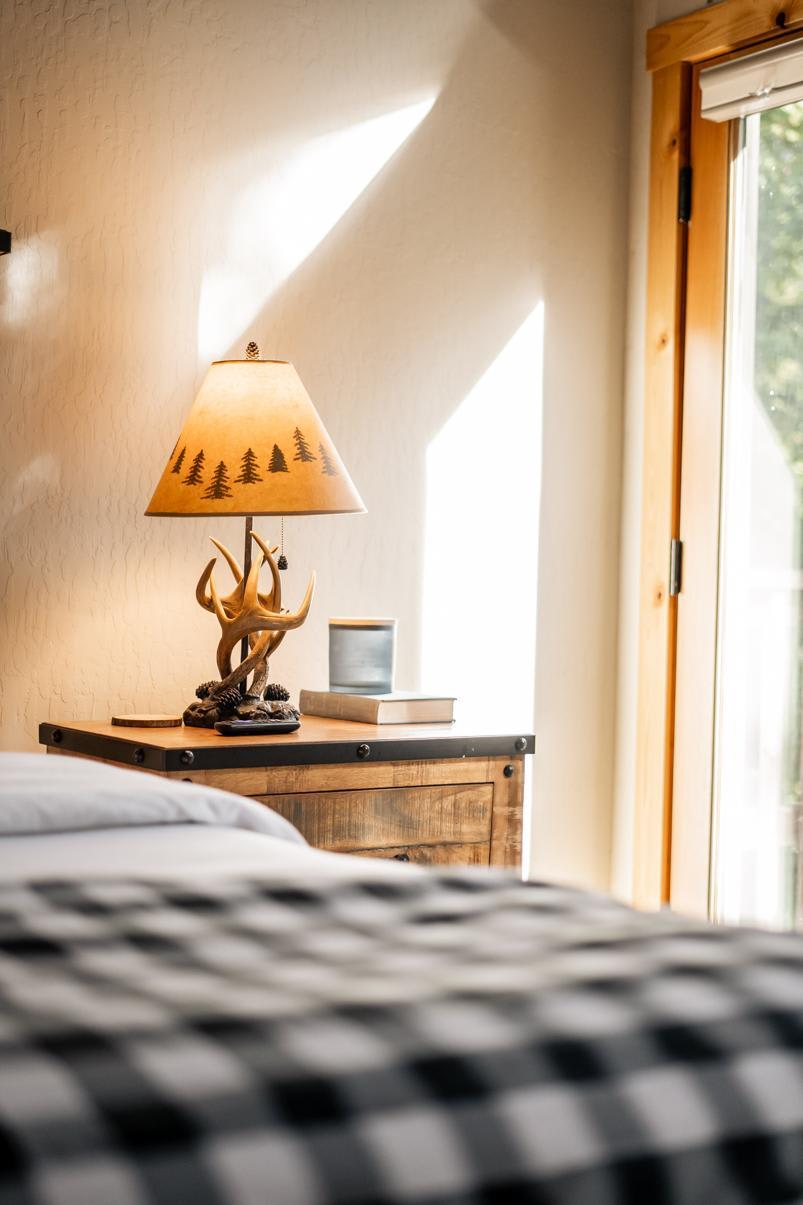 Cozy Truckee vacation rental room with rustic lamp and wooden nightstand, sunlight filtering through nearby window.