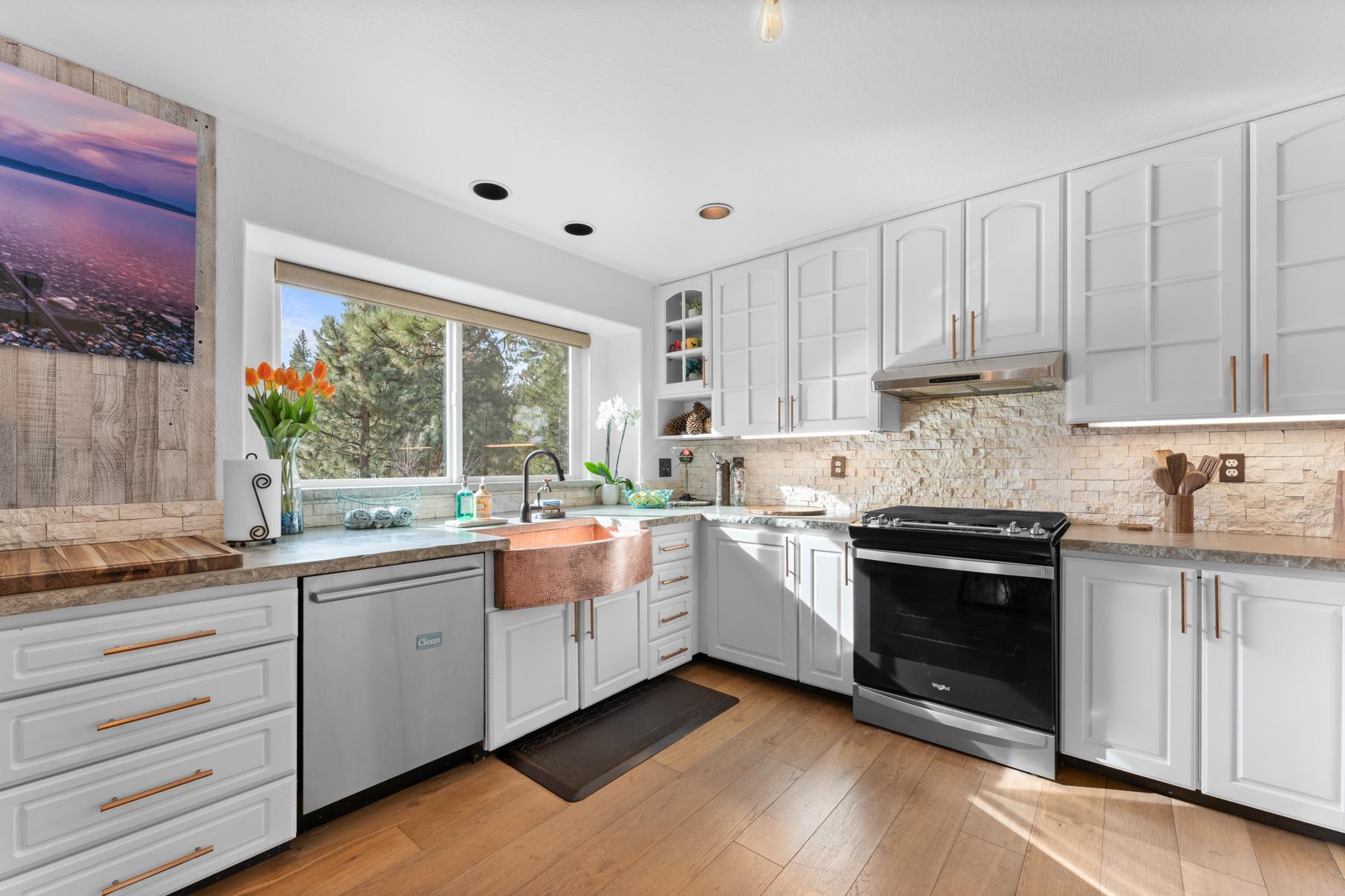 Kitchen of a Truckee vacation rental with copper sink, white cabinets, and large window with scenic view.