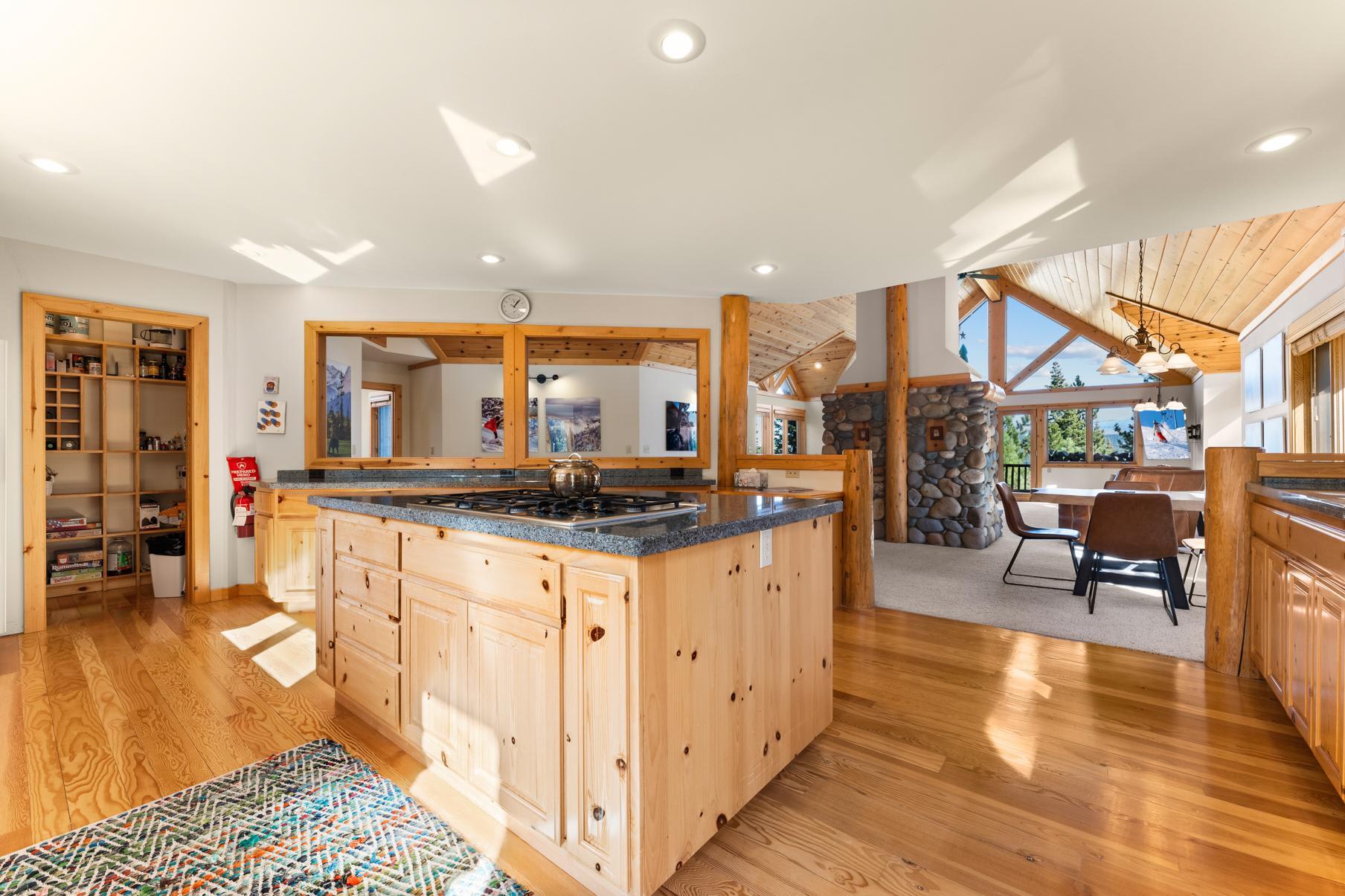 Spacious kitchen with wooden accents in a Truckee vacation rental, featuring a stone fireplace and large windows.