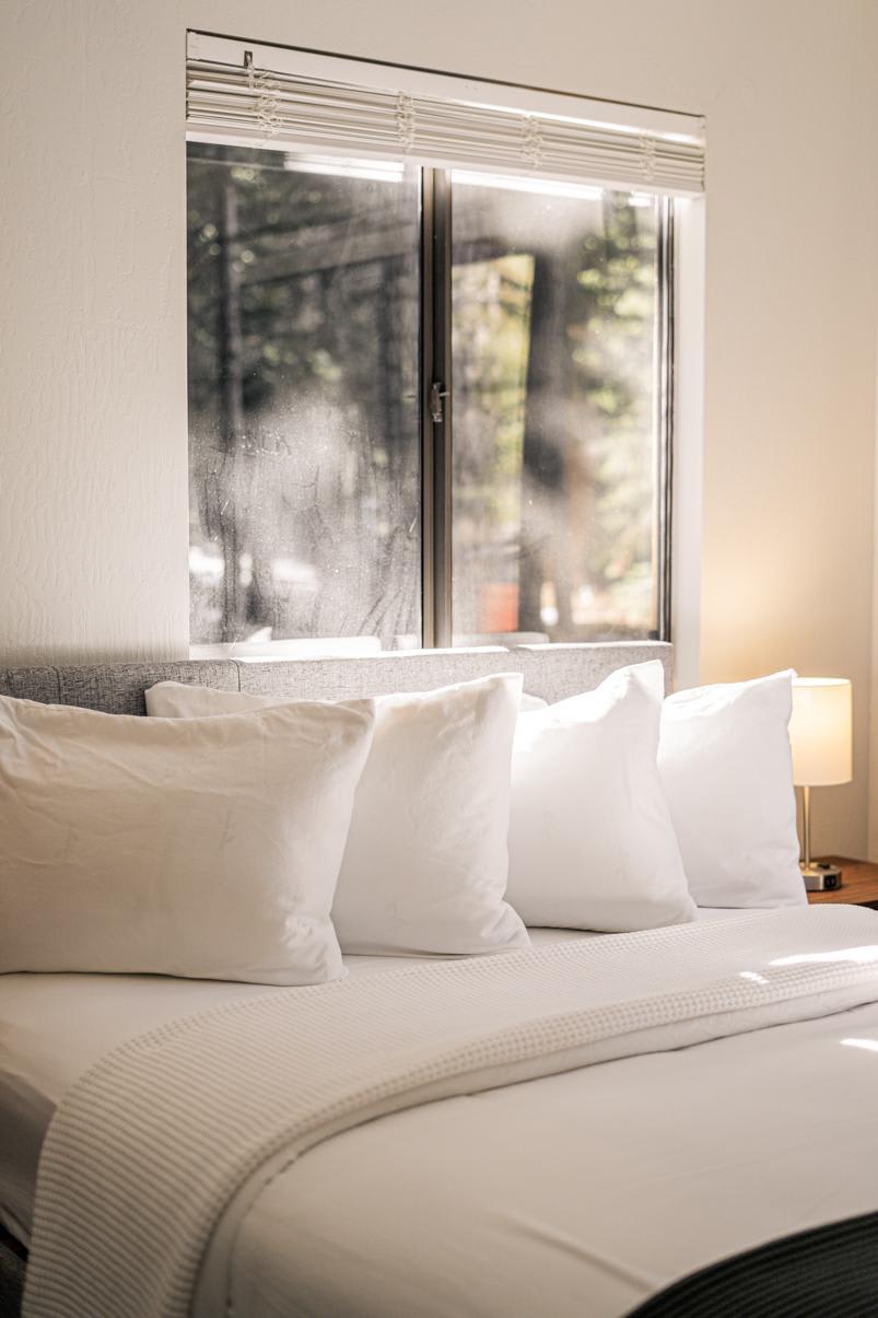 Cozy bedroom in a Tahoe Vista vacation rental with a bed, white pillows, and a window view of trees.