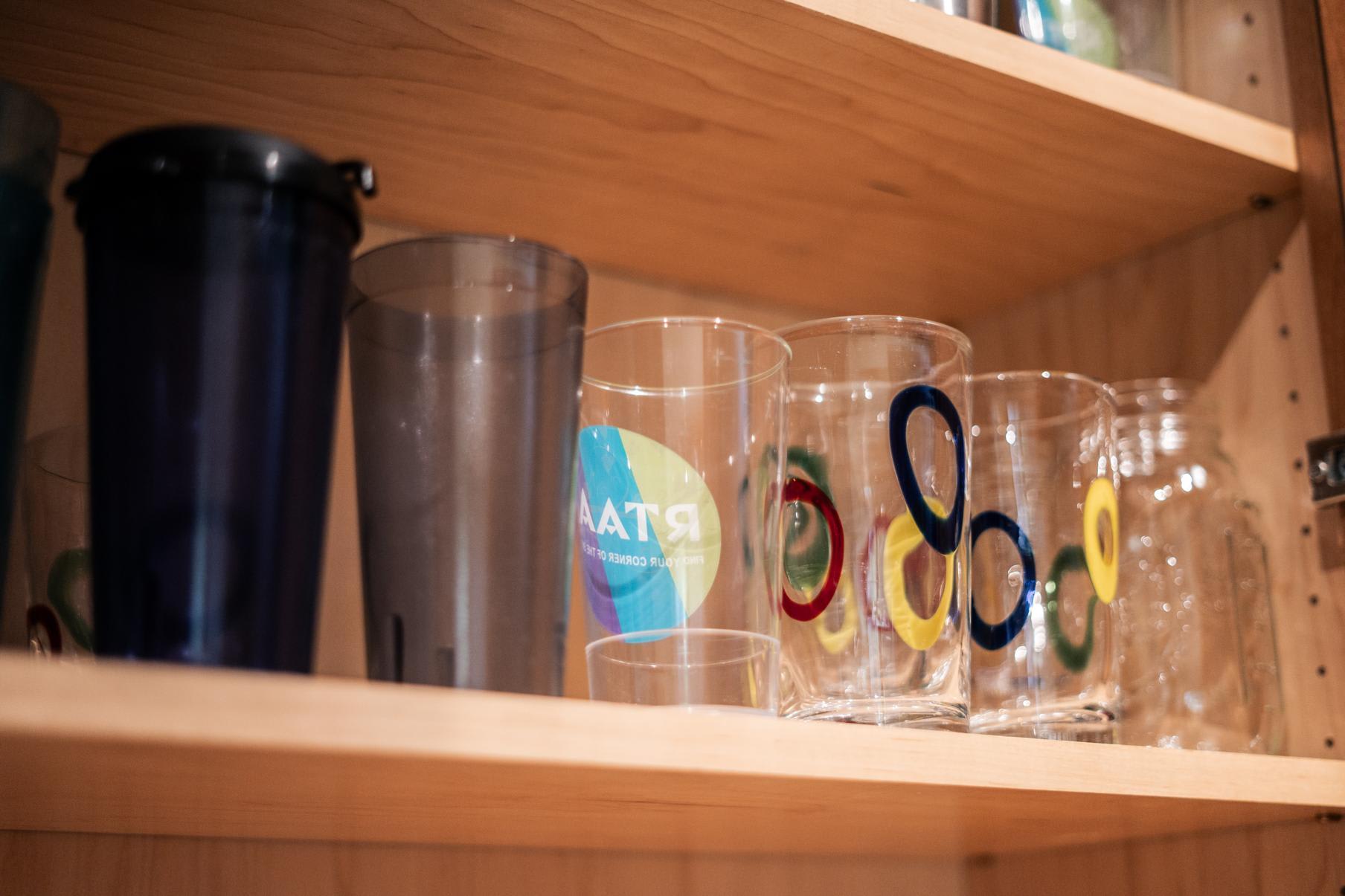 Colorful glasses on a wooden shelf in a Truckee vacation rental kitchen cabinet.