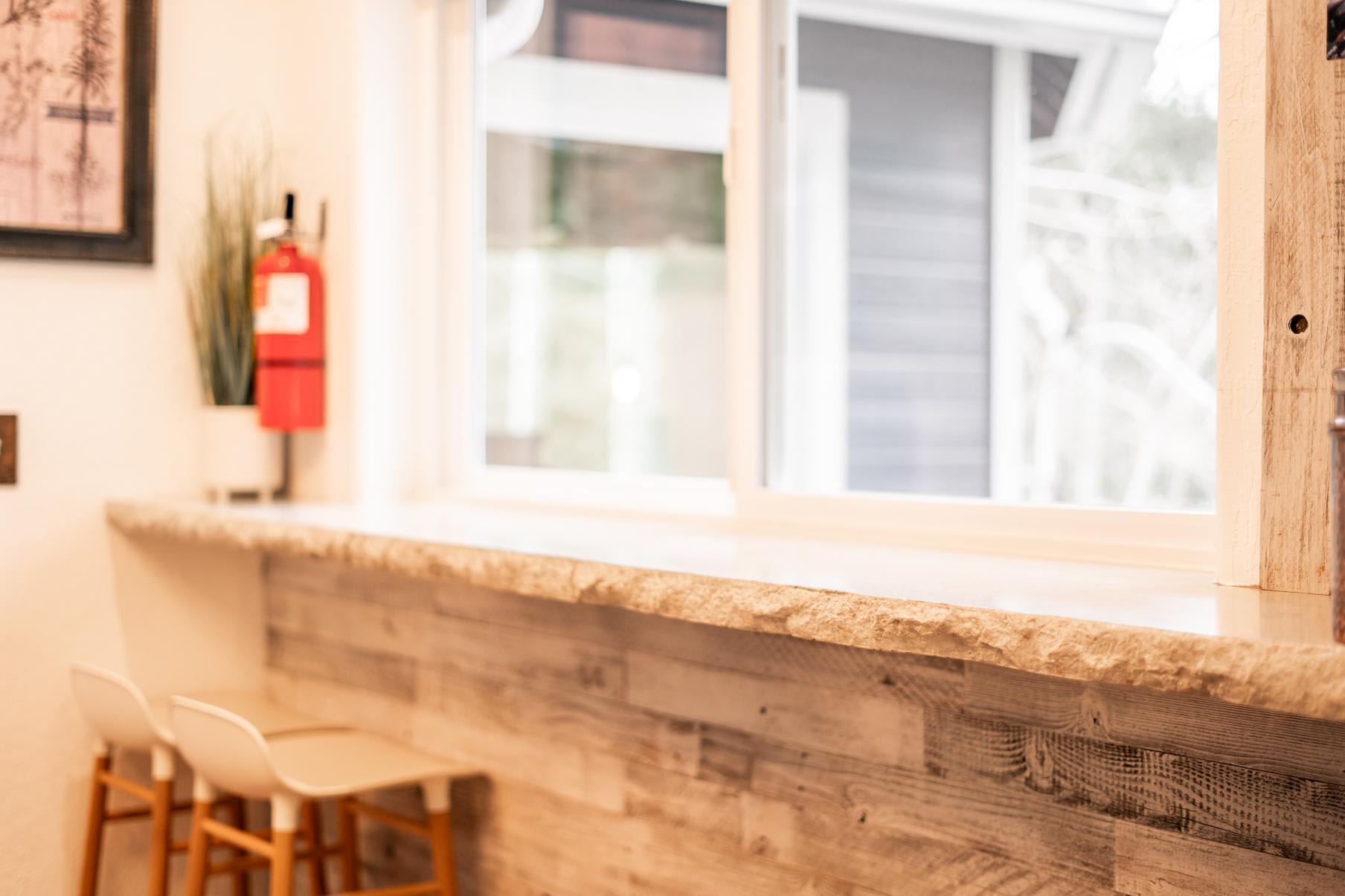 Cozy kitchen counter with stools in Truckee vacation rental, featuring rustic wood paneling and a large window.