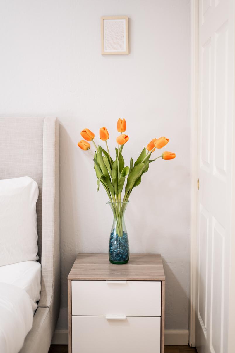 Vase of orange tulips on a bedside table in a Truckee vacation rental bedroom.