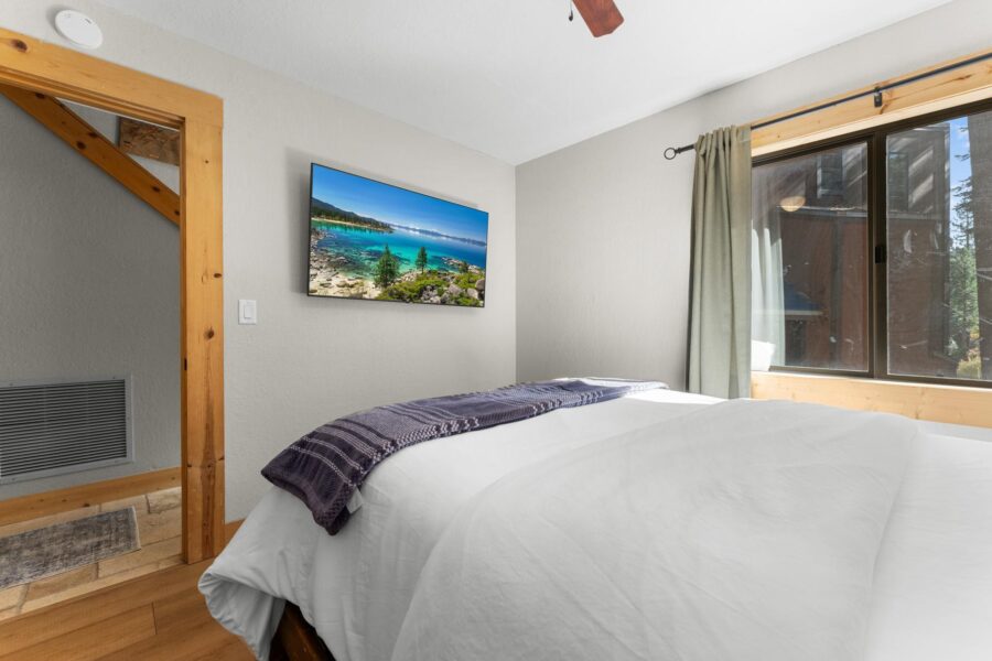 Bedroom in a Truckee vacation rental with a scenic landscape on the wall and a window view.