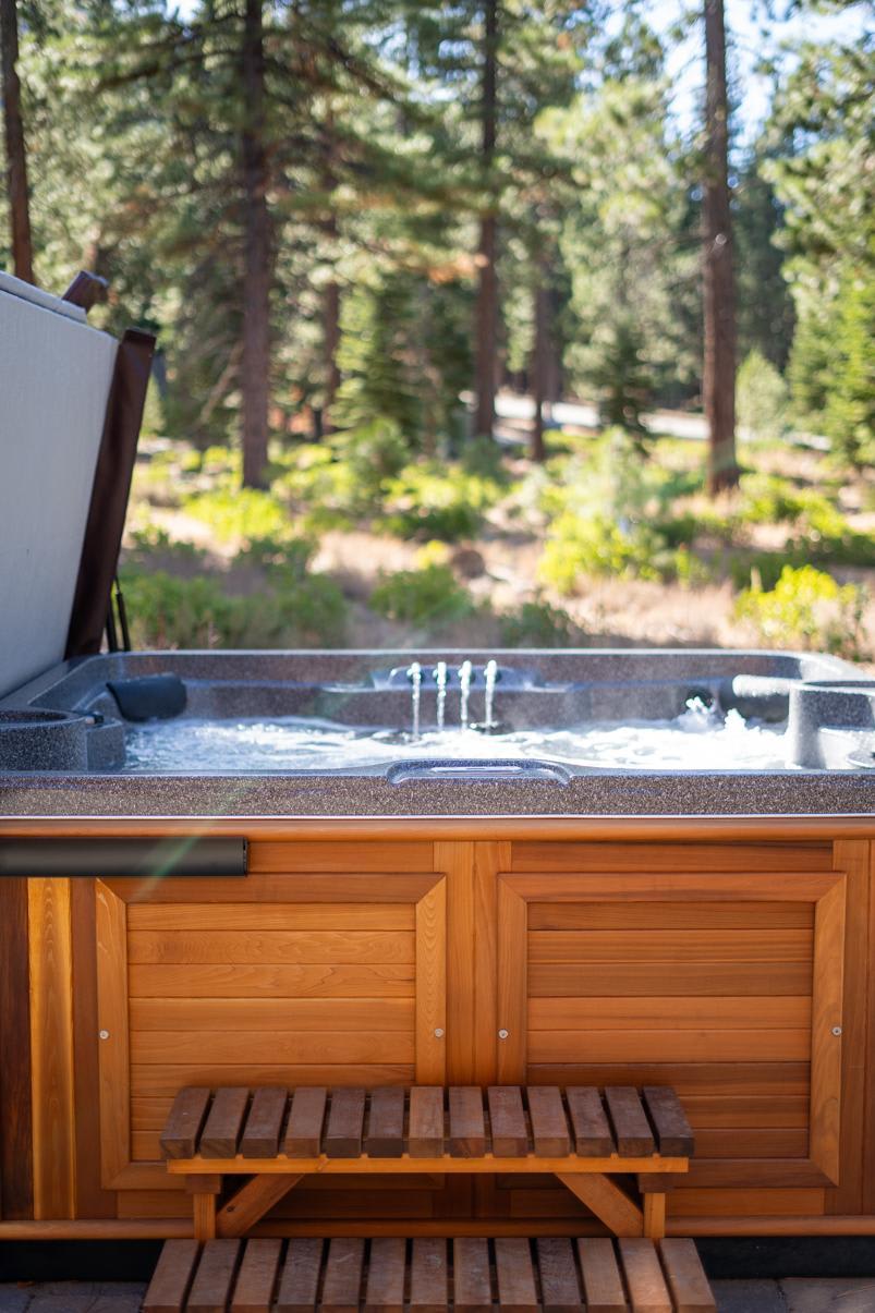 Hot tub at a Truckee vacation rental surrounded by tall pine trees and a serene forest setting.