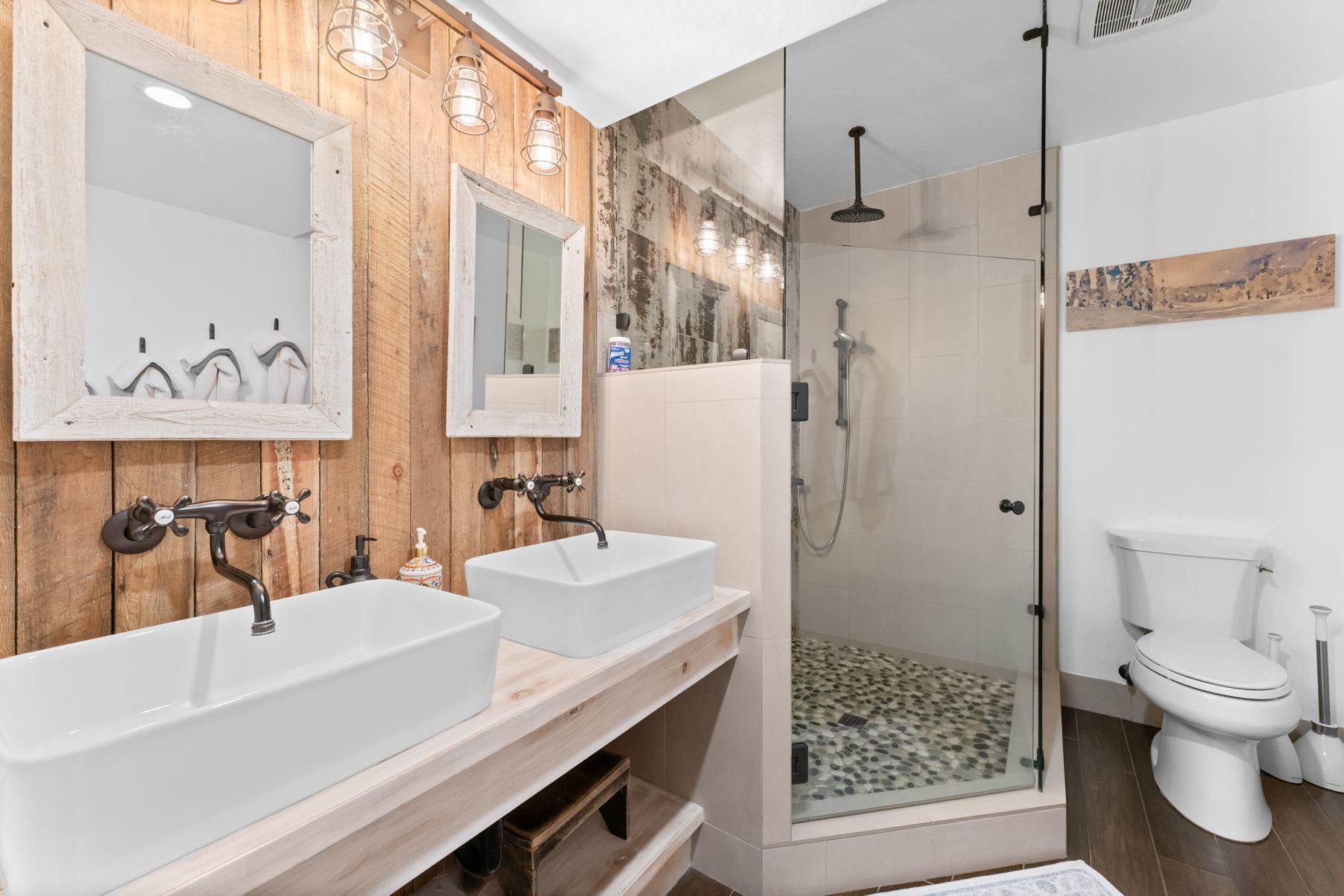 Modern bathroom in a Truckee vacation rental with double sinks, wood accents, and a glass-enclosed shower.