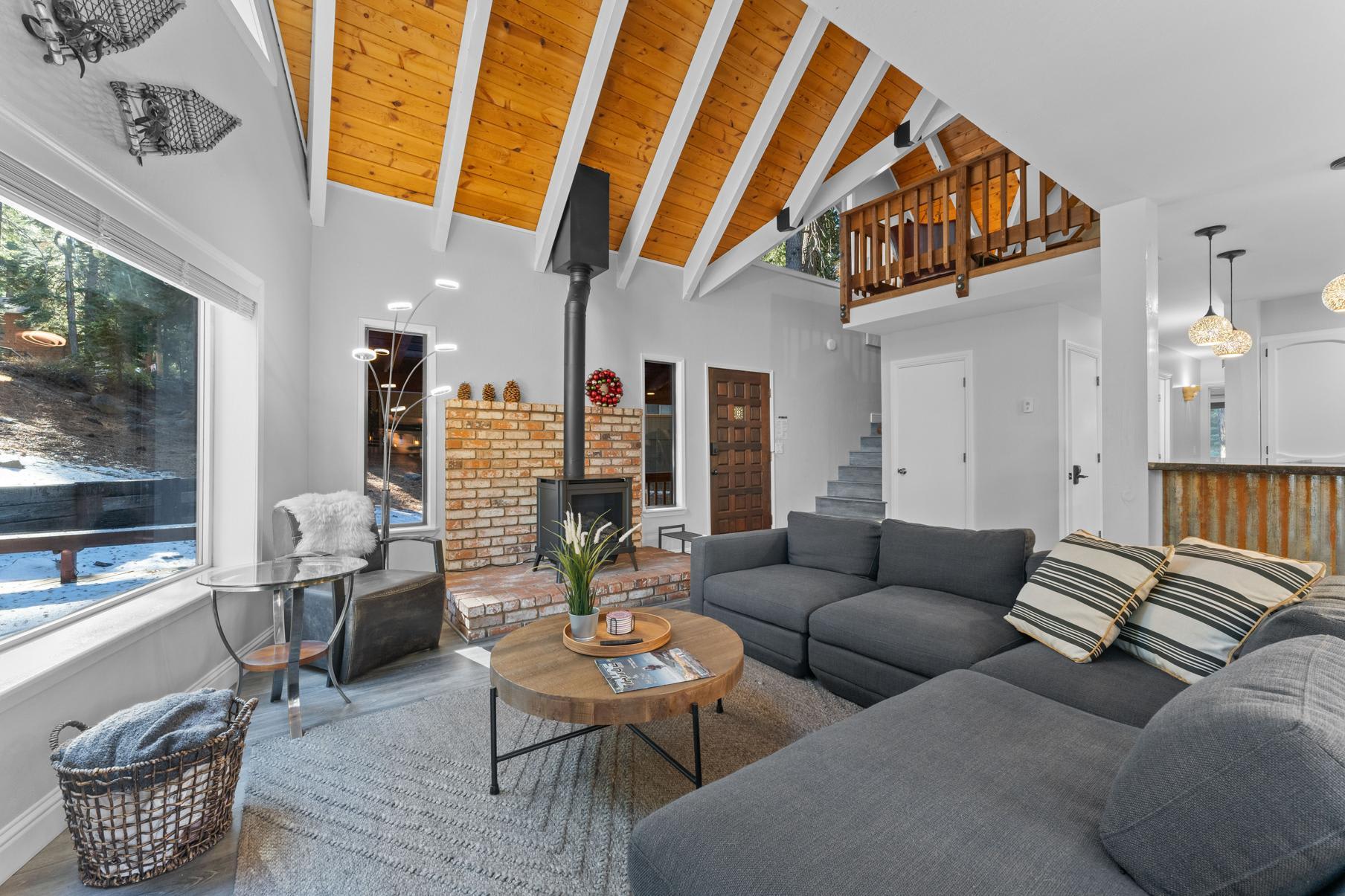 Cozy interior of a Tahoe Vista vacation rental with a brick fireplace, gray sectional sofa, and rustic wood accents.