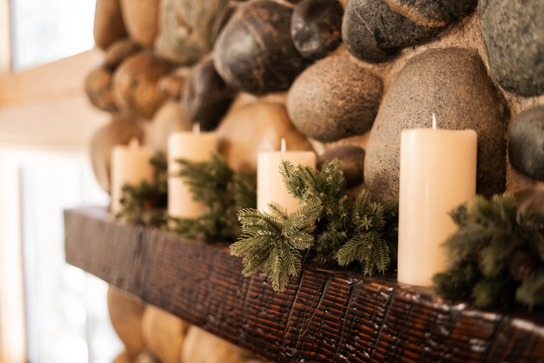 Candles and greenery on a stone fireplace mantel in a Truckee vacation rental.