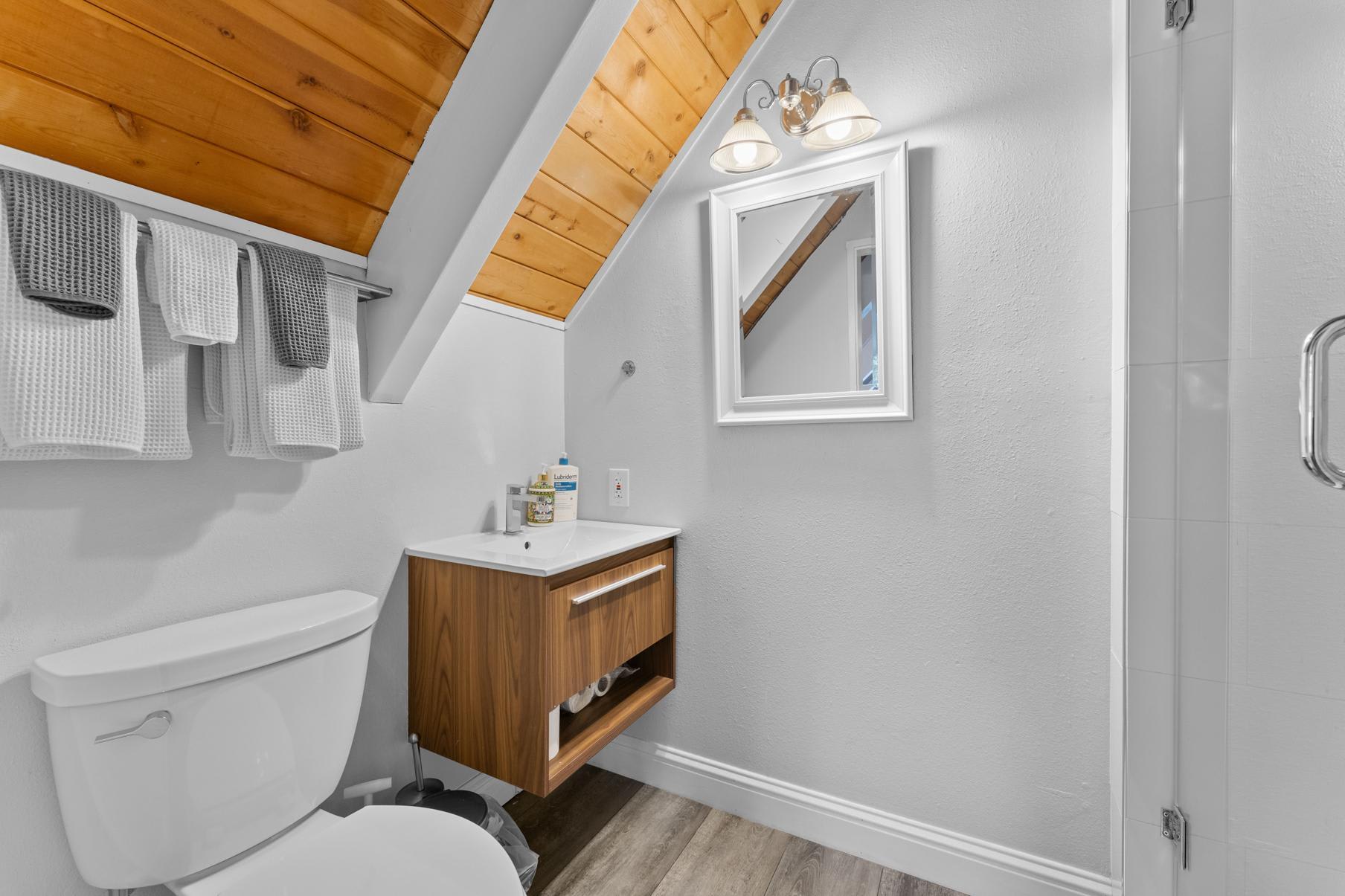 Bathroom in a Tahoe Vista vacation rental, featuring a modern sink, toilet, and towels on a wooden accent wall.