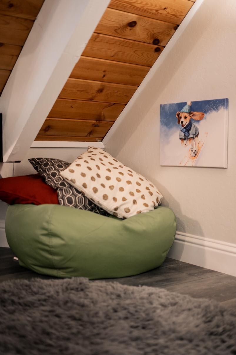 Cozy nook in Tahoe Vista vacation rental with bean bag, pillows, and a fun dog ski painting under a wooden ceiling.