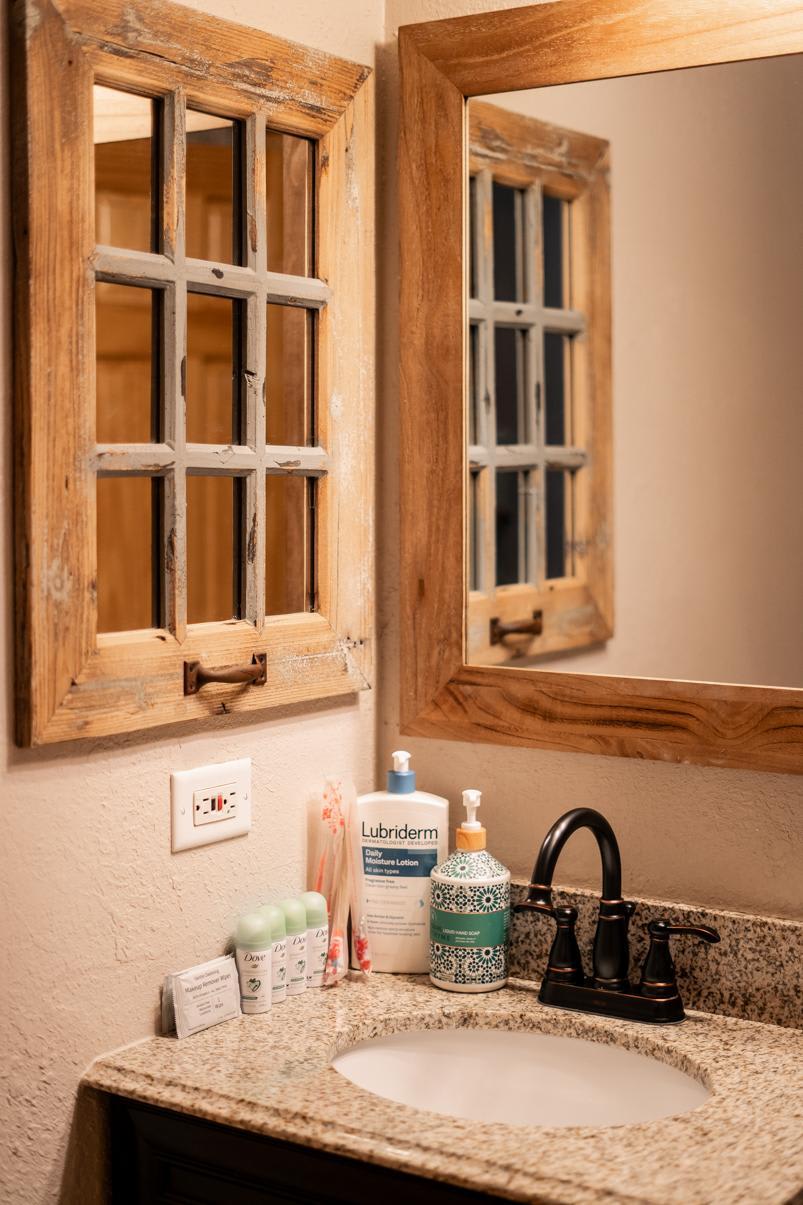 Rustic bathroom sink area in Truckee vacation rental, featuring wooden mirrors and toiletries on a granite countertop.