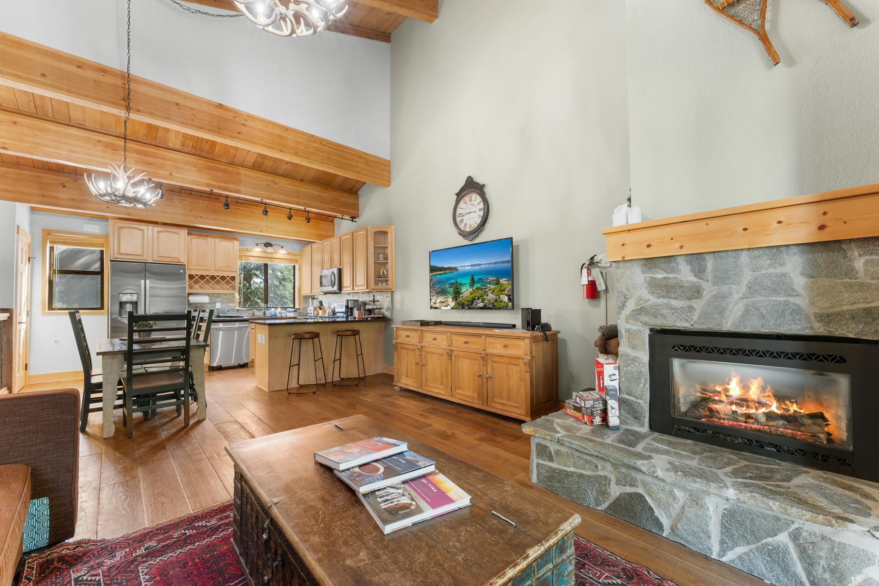 Cozy Truckee vacation rental with a stone fireplace, wooden beams, and a modern kitchen, perfect for relaxation.