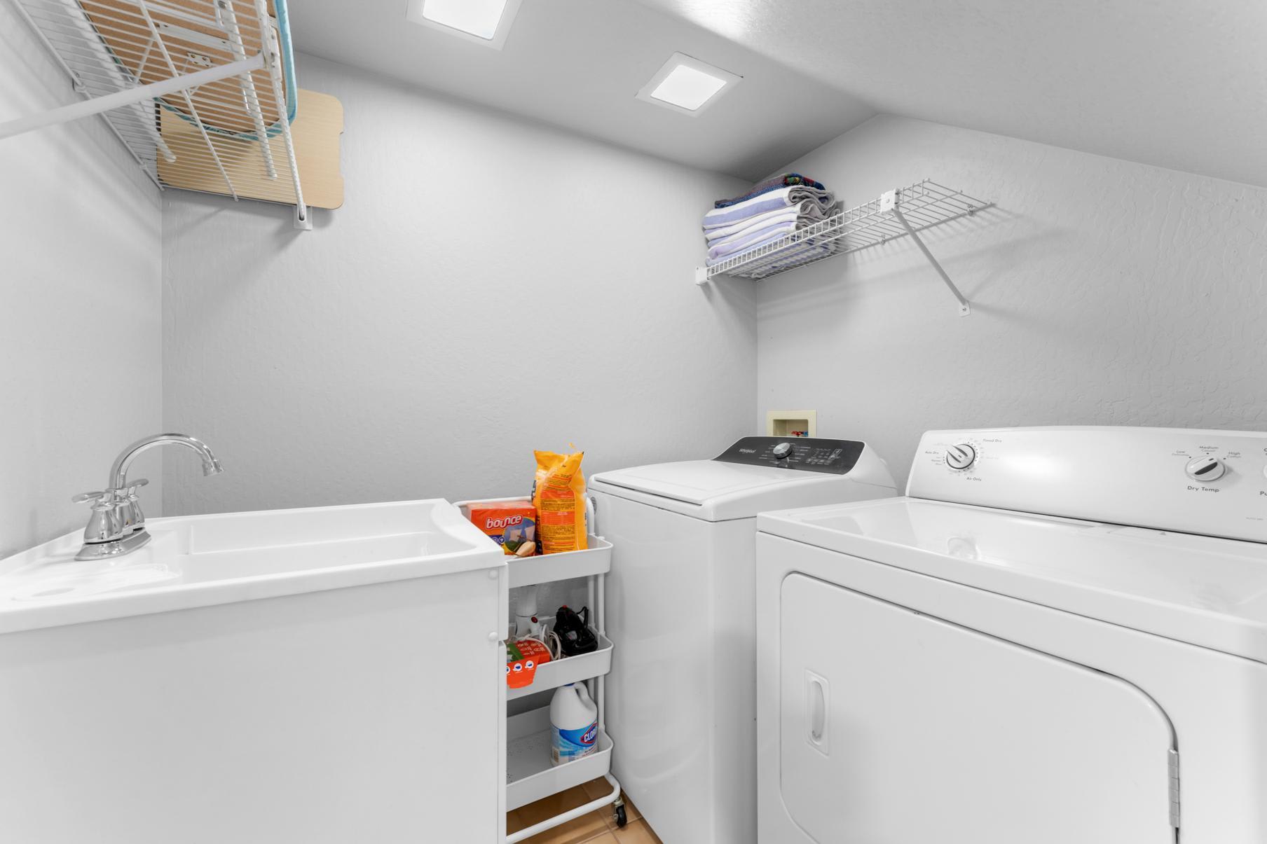 Laundry room in a Truckee vacation rental with a washer, dryer, and sink, featuring neatly organized shelves.