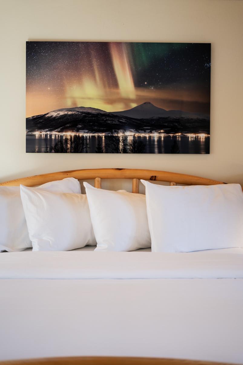 Cozy bedroom in a Truckee vacation rental with a scenic aurora photo above the wooden bed frame.