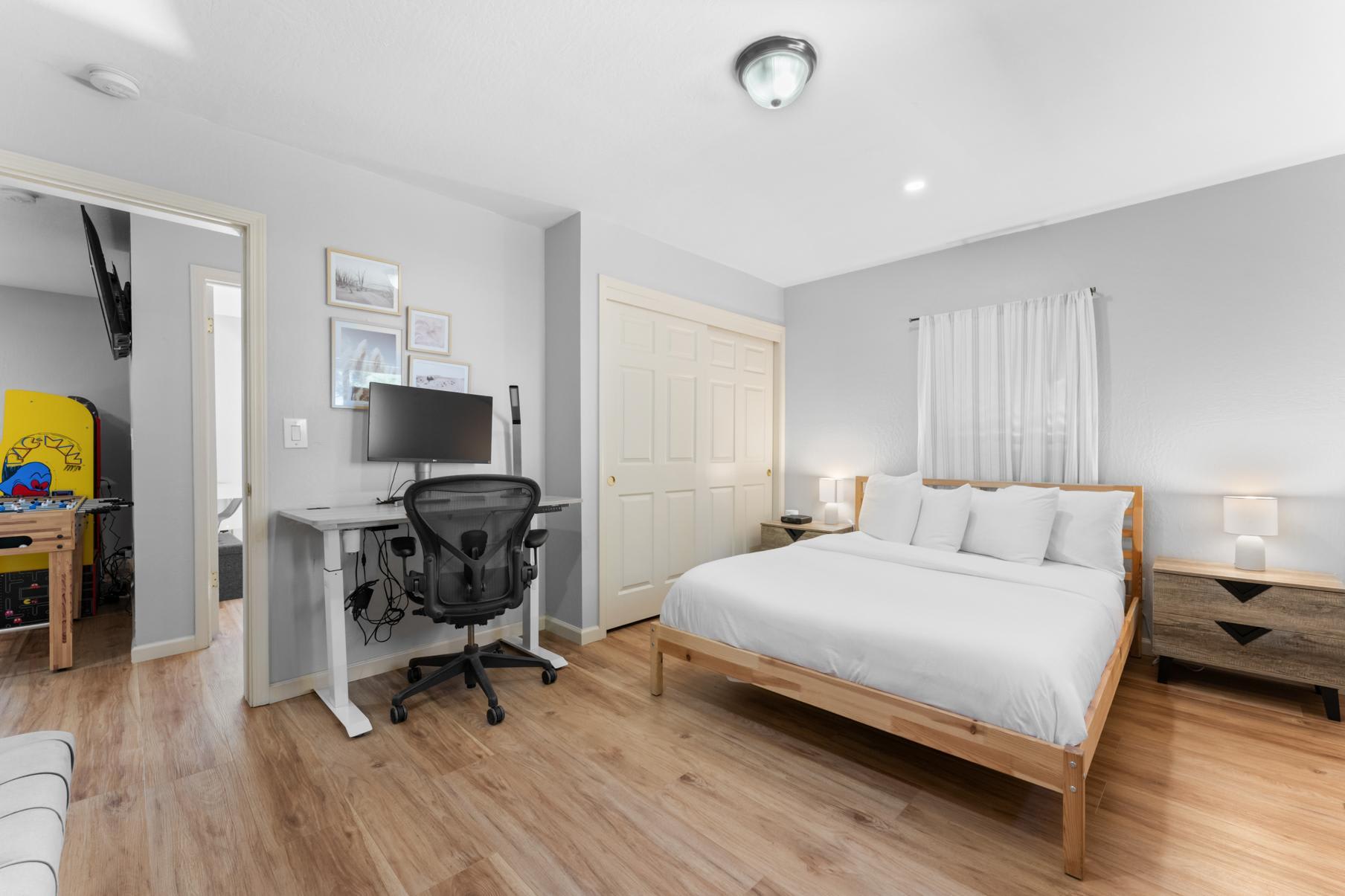 Modern bedroom in Truckee vacation rental with a bed, desk, and chair, featuring neutral tones and wooden flooring.